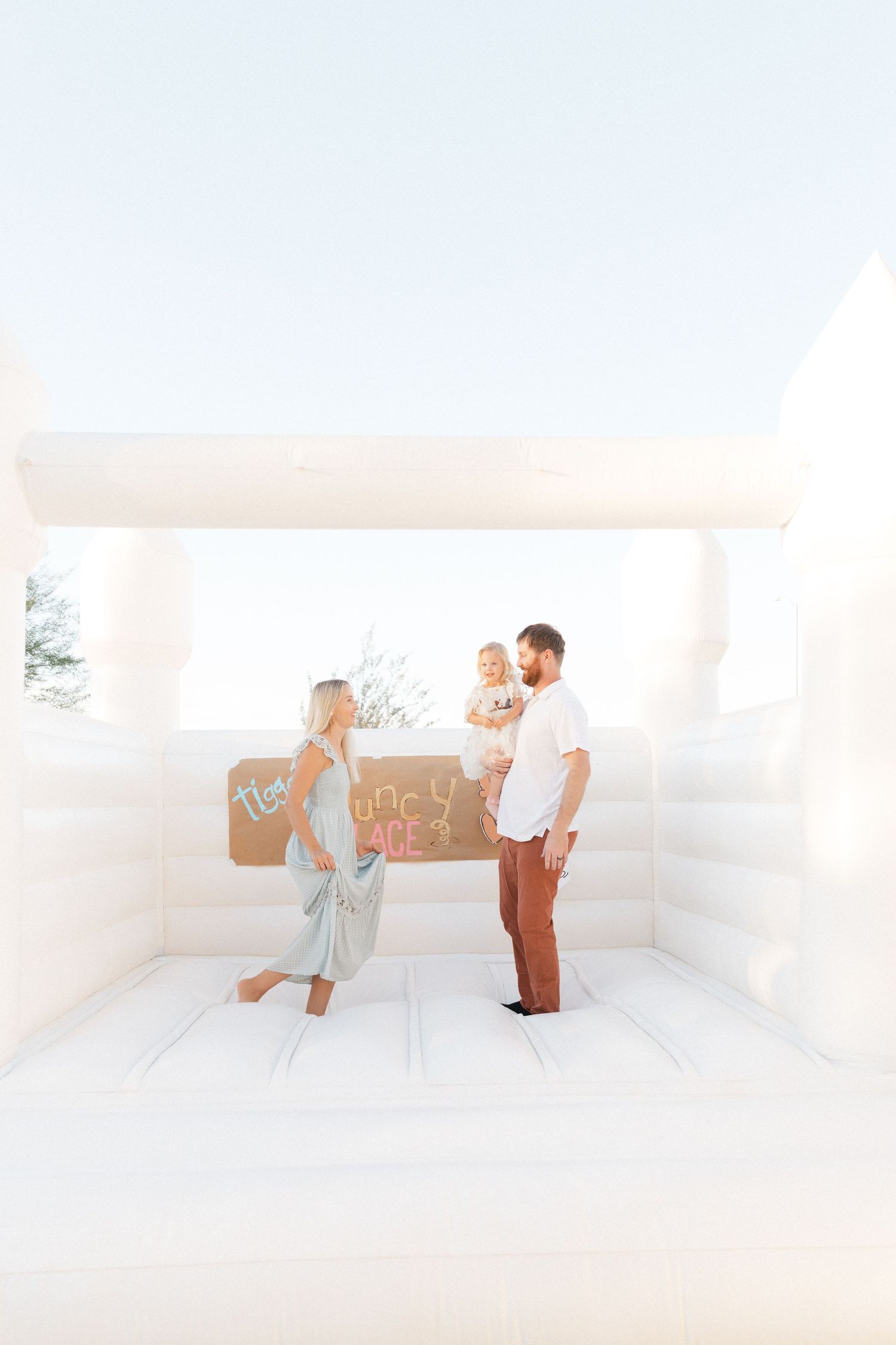 Minimalist white studio photoshoot showing figures in casual attire interacting in bright, airy space.