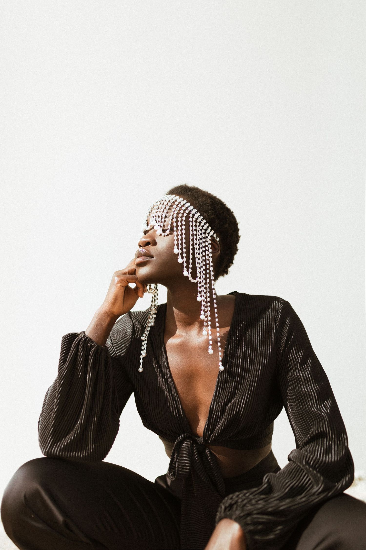 Fashion portrait featuring model in black outfit with dramatic pearl headpiece.