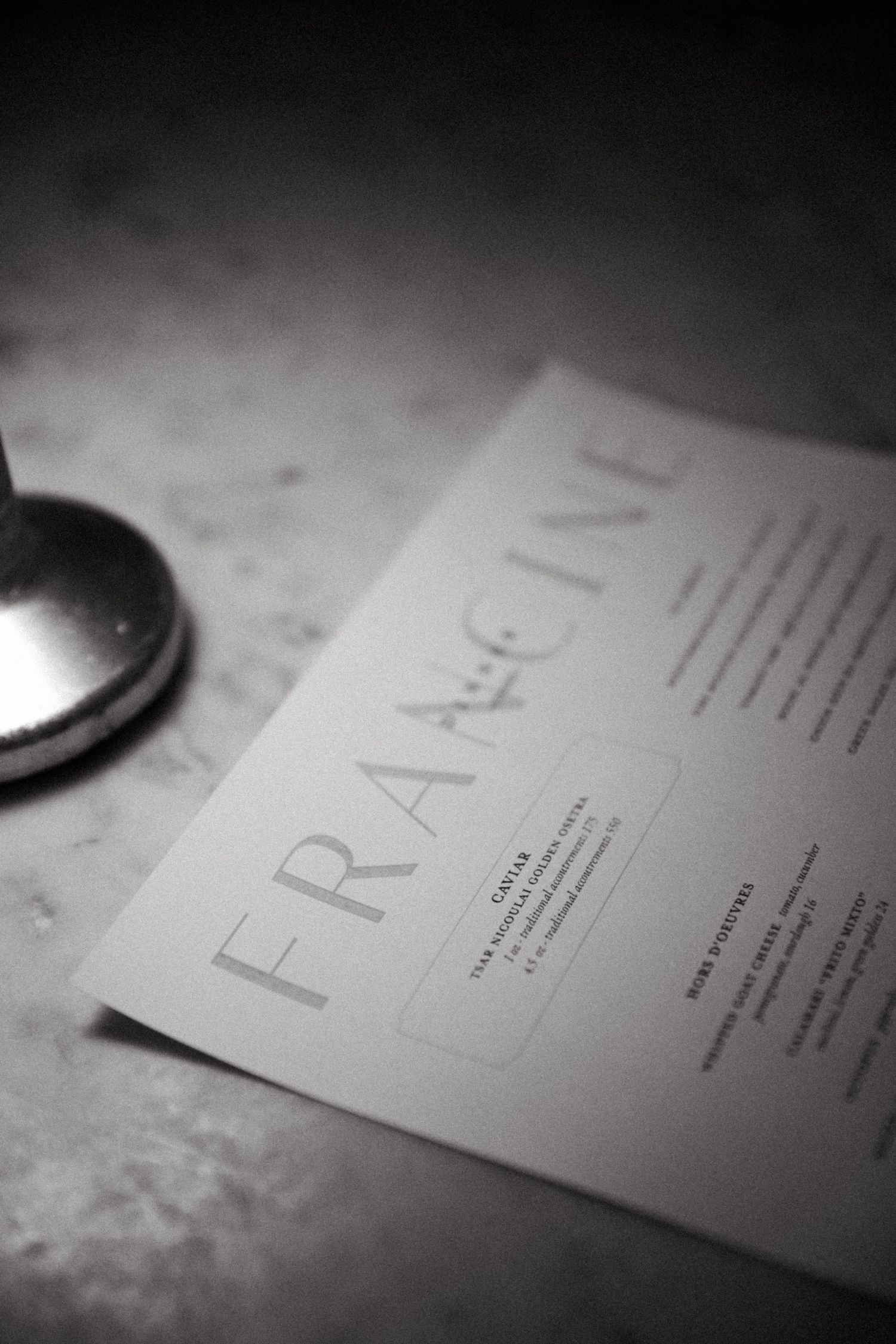 Black and white close-up of a menu with 'FRAGINE' text visible.