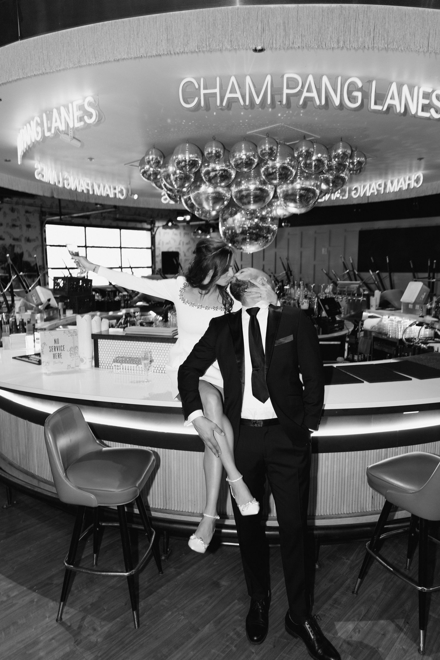 A black and white photo of a couple at a vintage-style bowling alley bar.