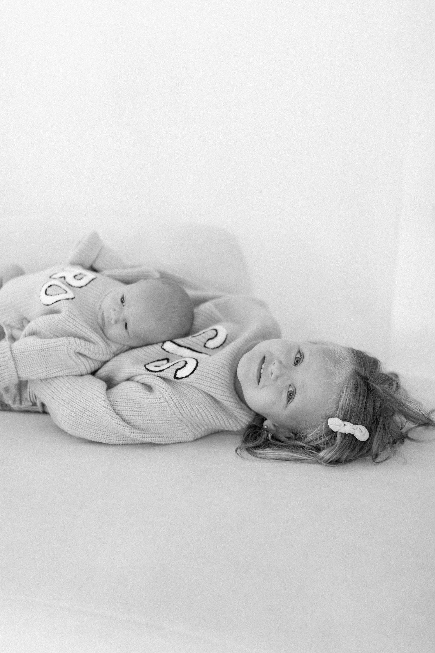 Four black and white photos showing someone lying on their side against a white background in soft, minimalist composition.