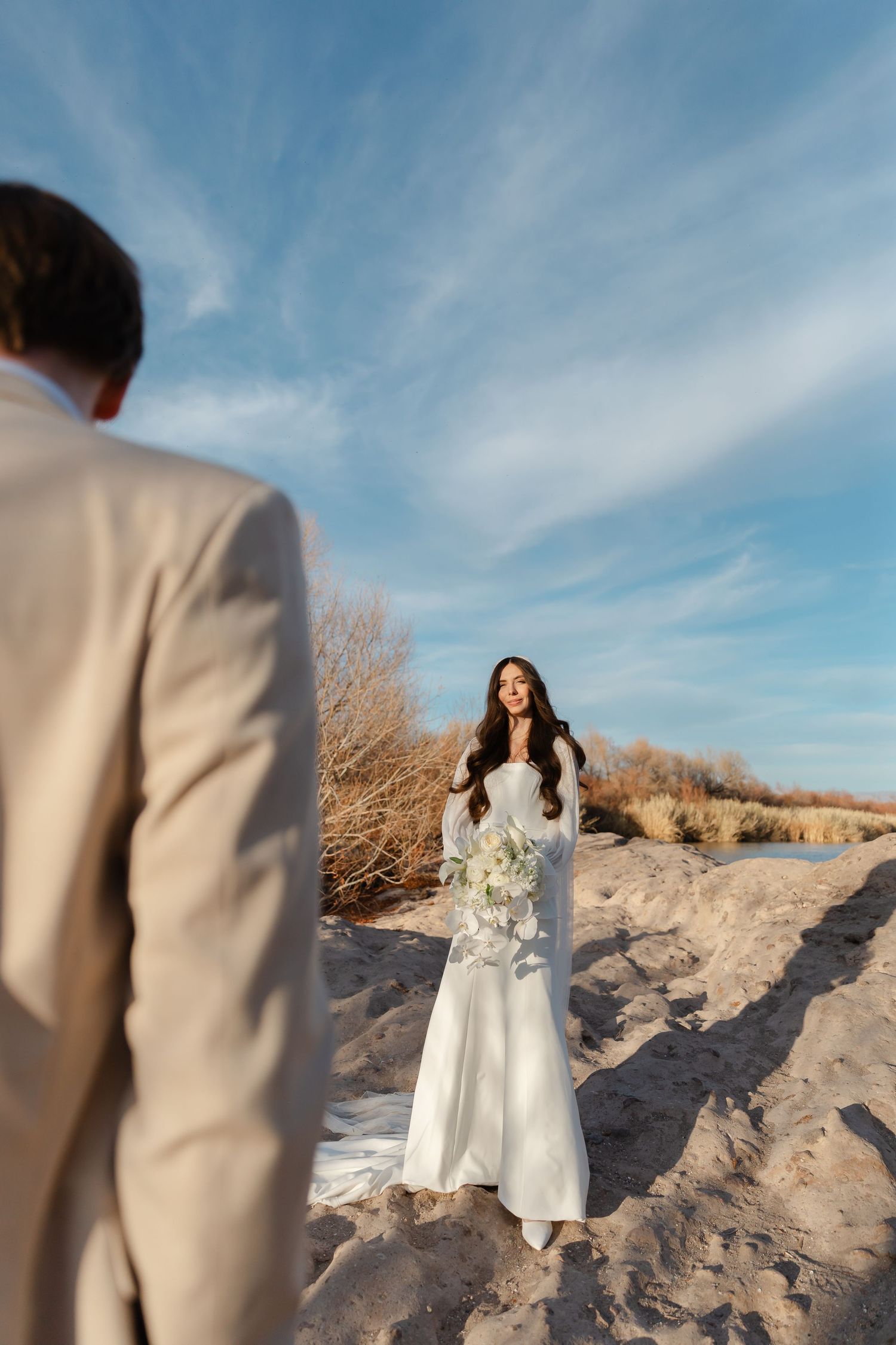 A series of wedding photos showing a couple in white and beige attire posing against sandy dunes and blue sky.