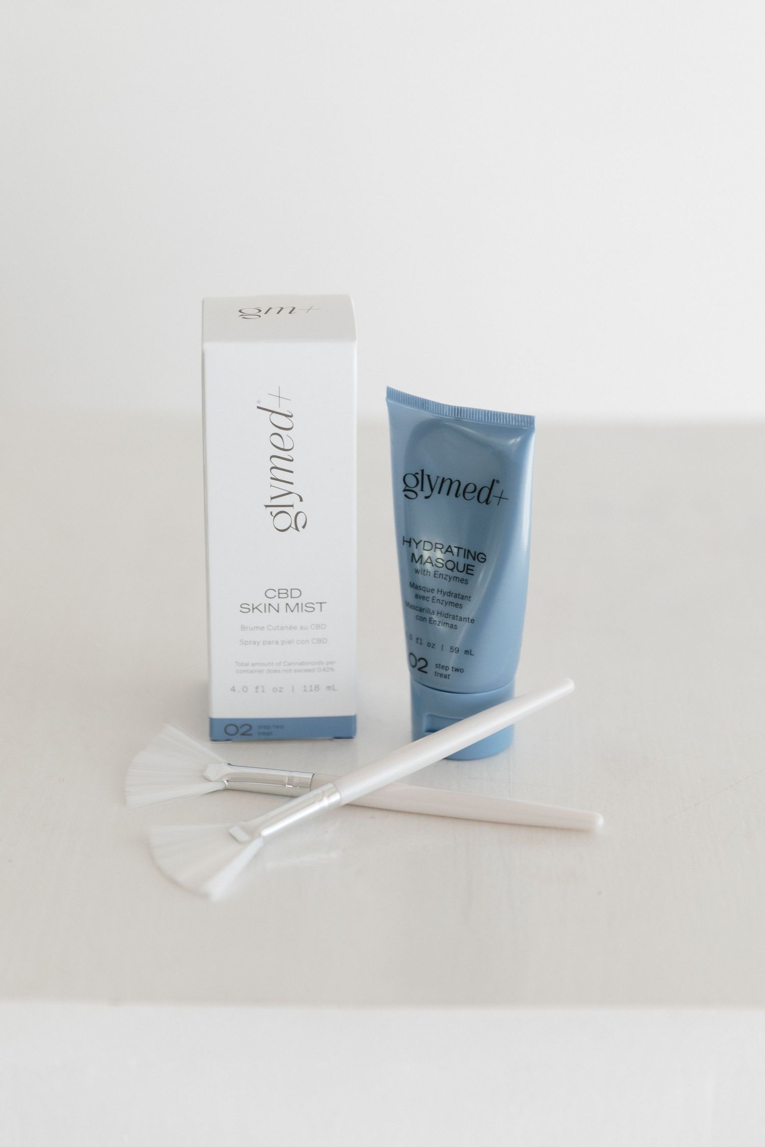 A minimalist product photography series showing blue skincare tubes and white packaging against a light background.