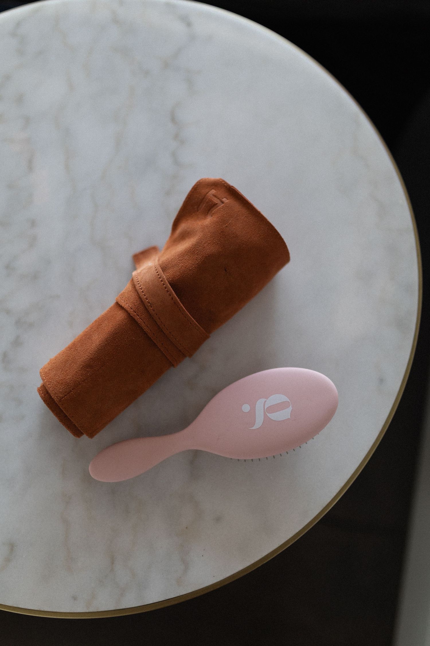 Pink and copper metal hair clips in various positions displayed on a marble surface with gold trim.
