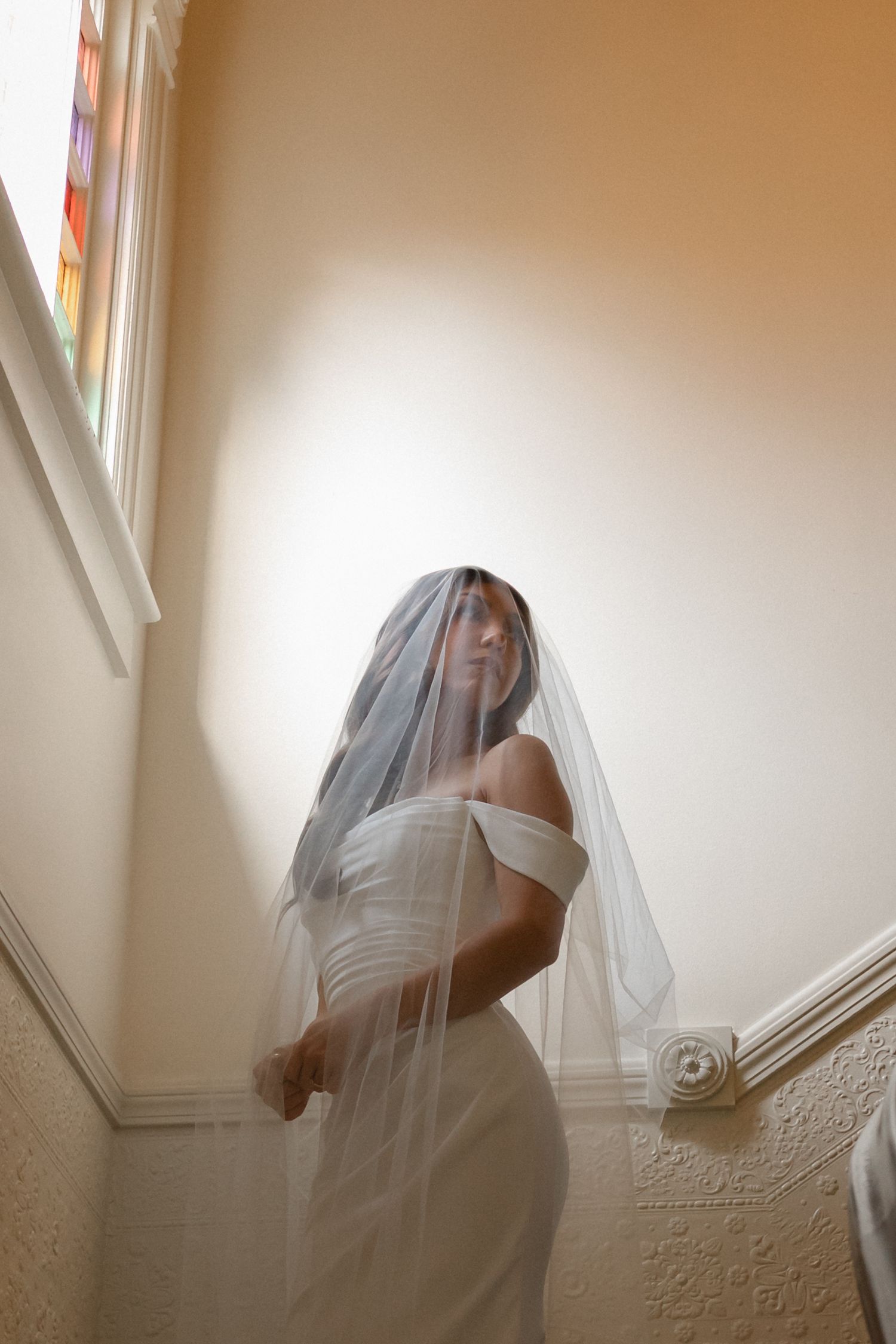 A series of five sequential photos showing a person covered in white fabric moving against a beige wall.