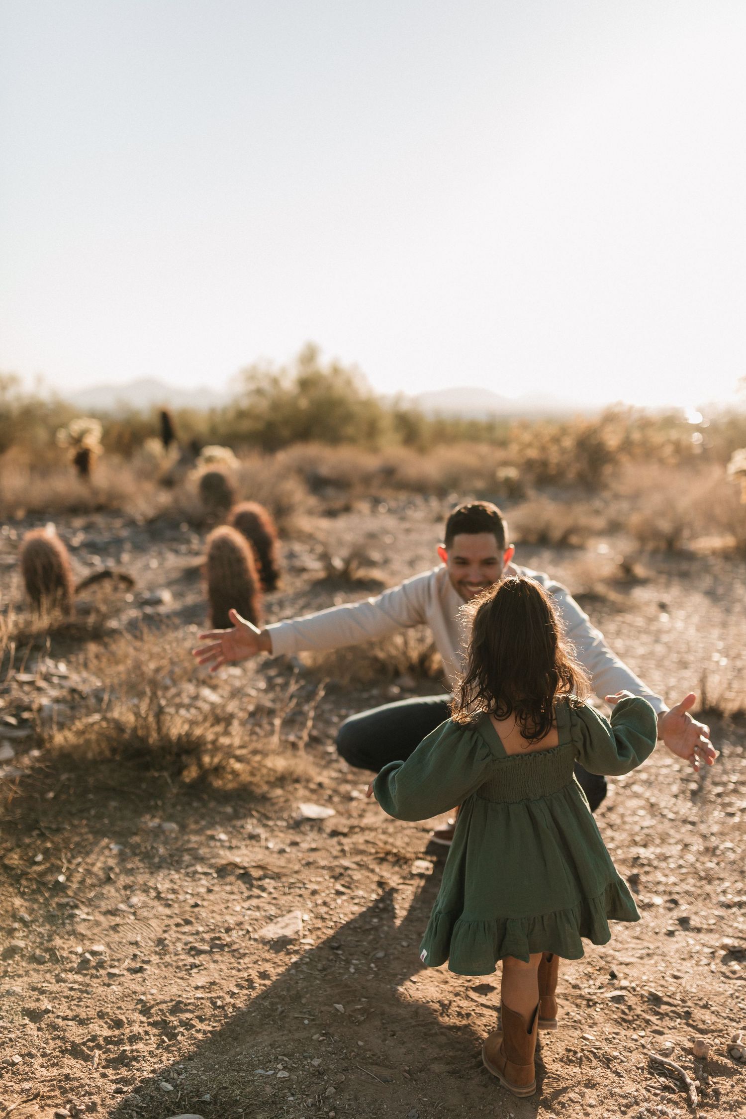 A sequence of photos showing a child in a green dress twirling and dancing outdoors at sunset in a desert landscape.
