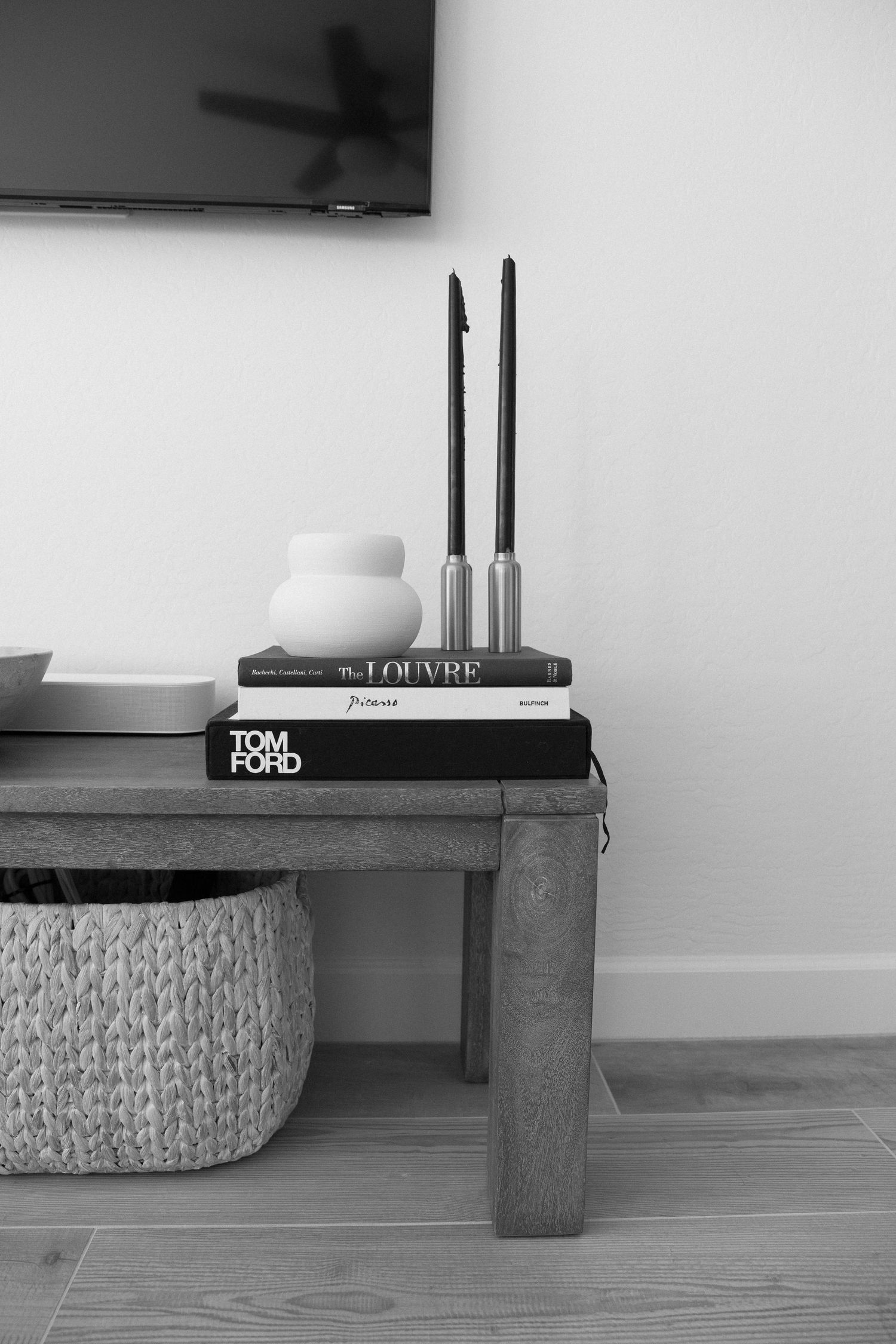 Monochromatic styling vignette with black candles and design books on wooden surface.