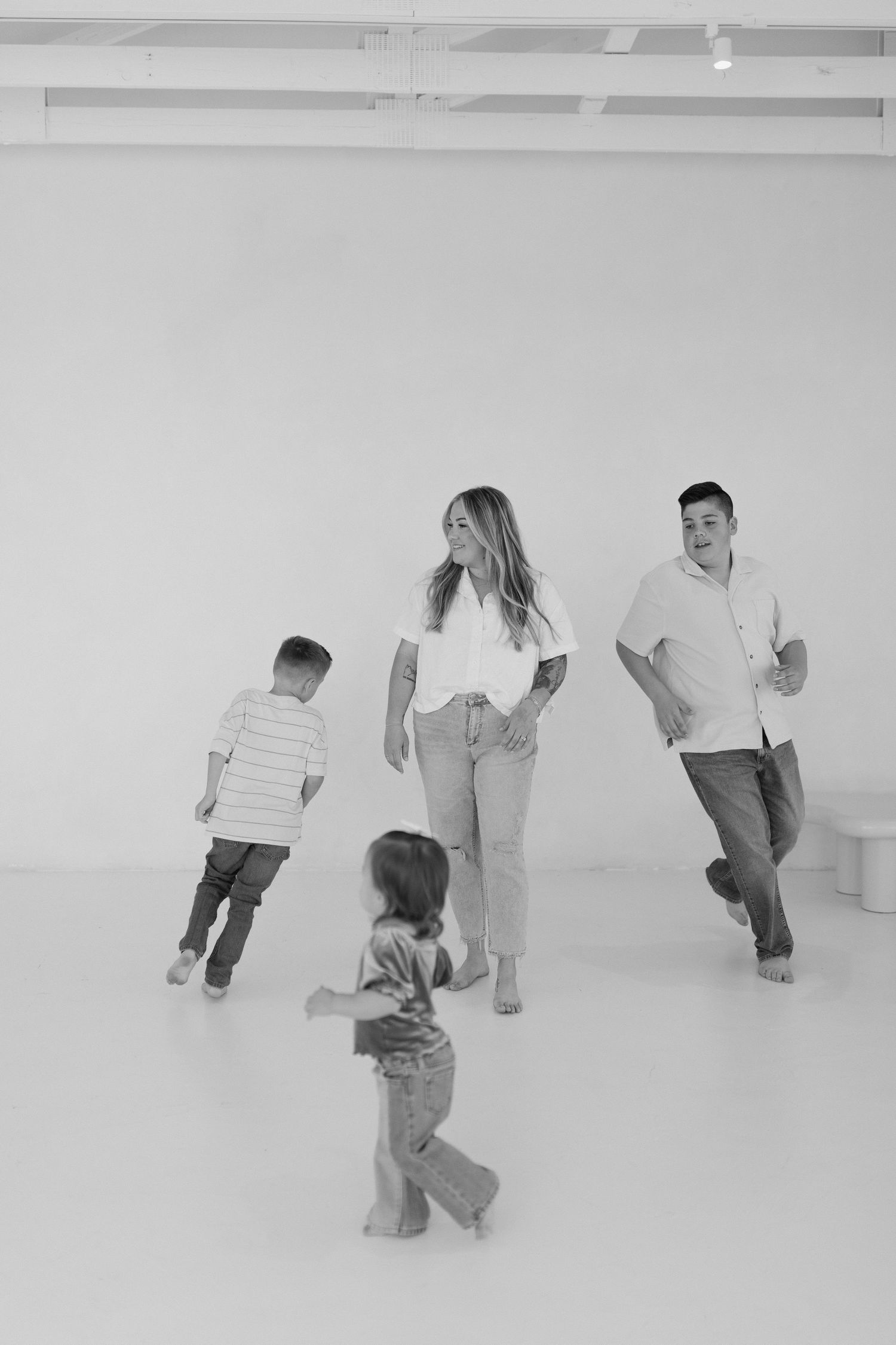 Family dancing and moving together in a minimalist white studio space shot in black and white photography.