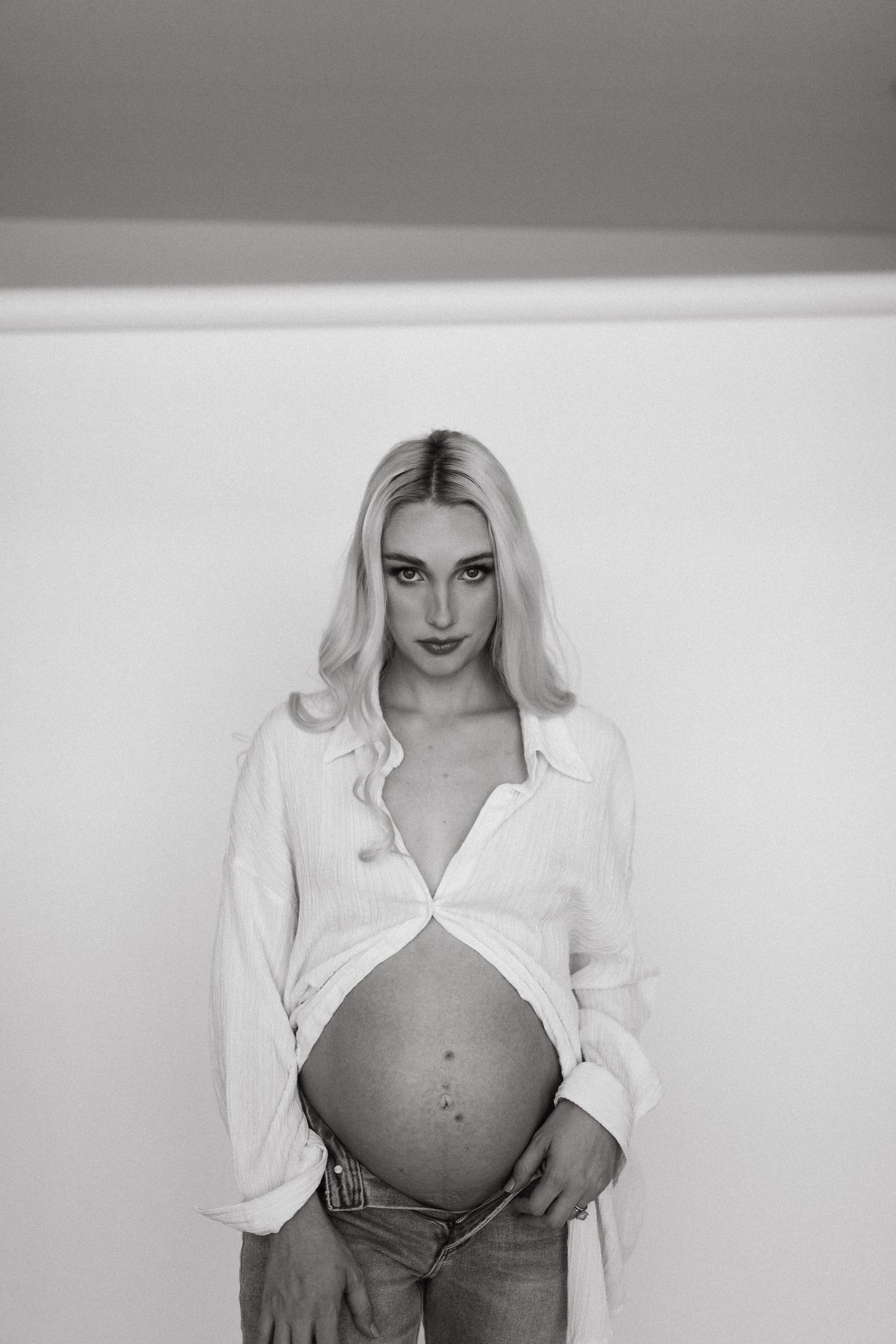 Artistic black and white maternity photo showcasing bare pregnant belly.
