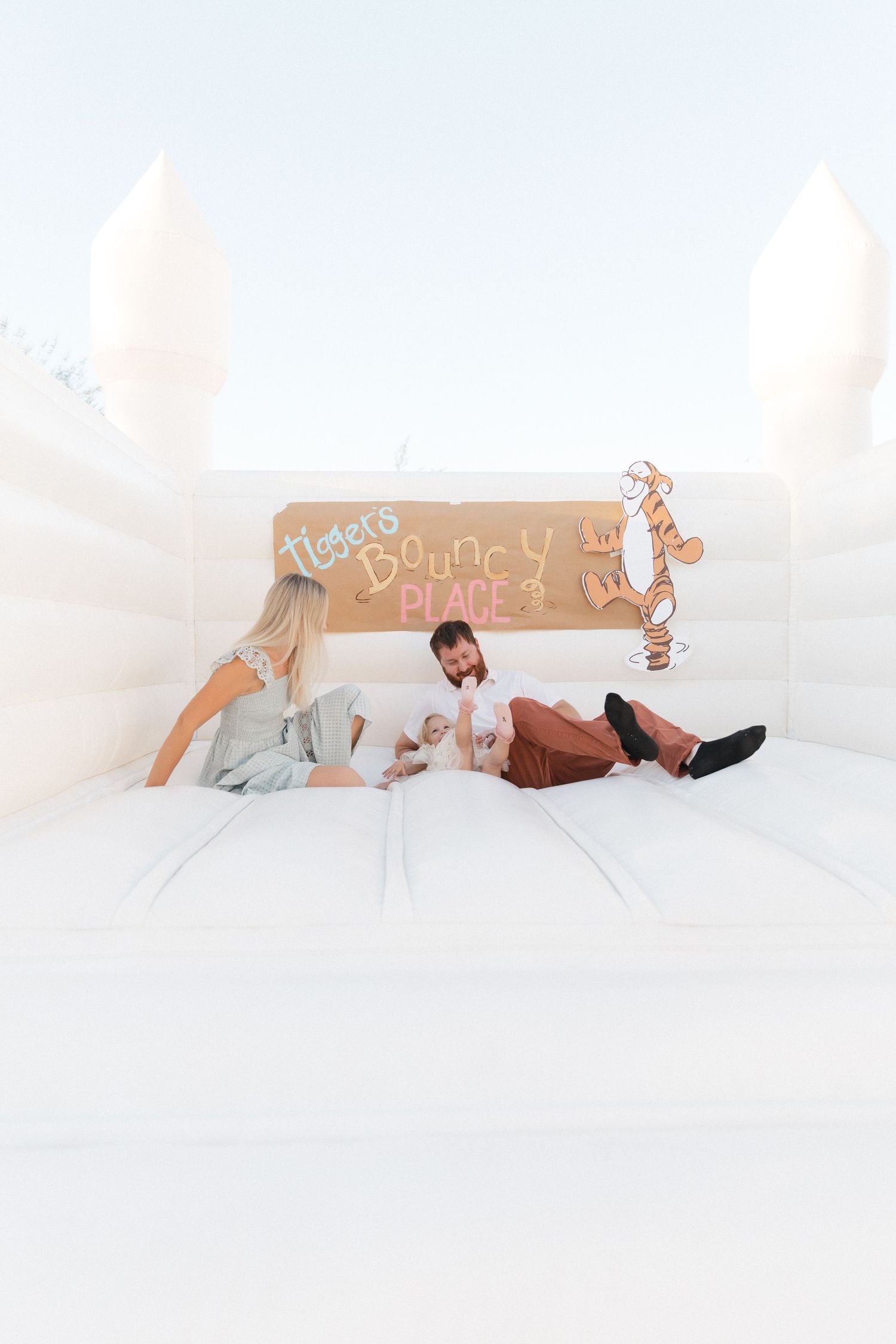 People in white outfits lie down on a white surface in a bright, minimalist setting creating a serene atmosphere.