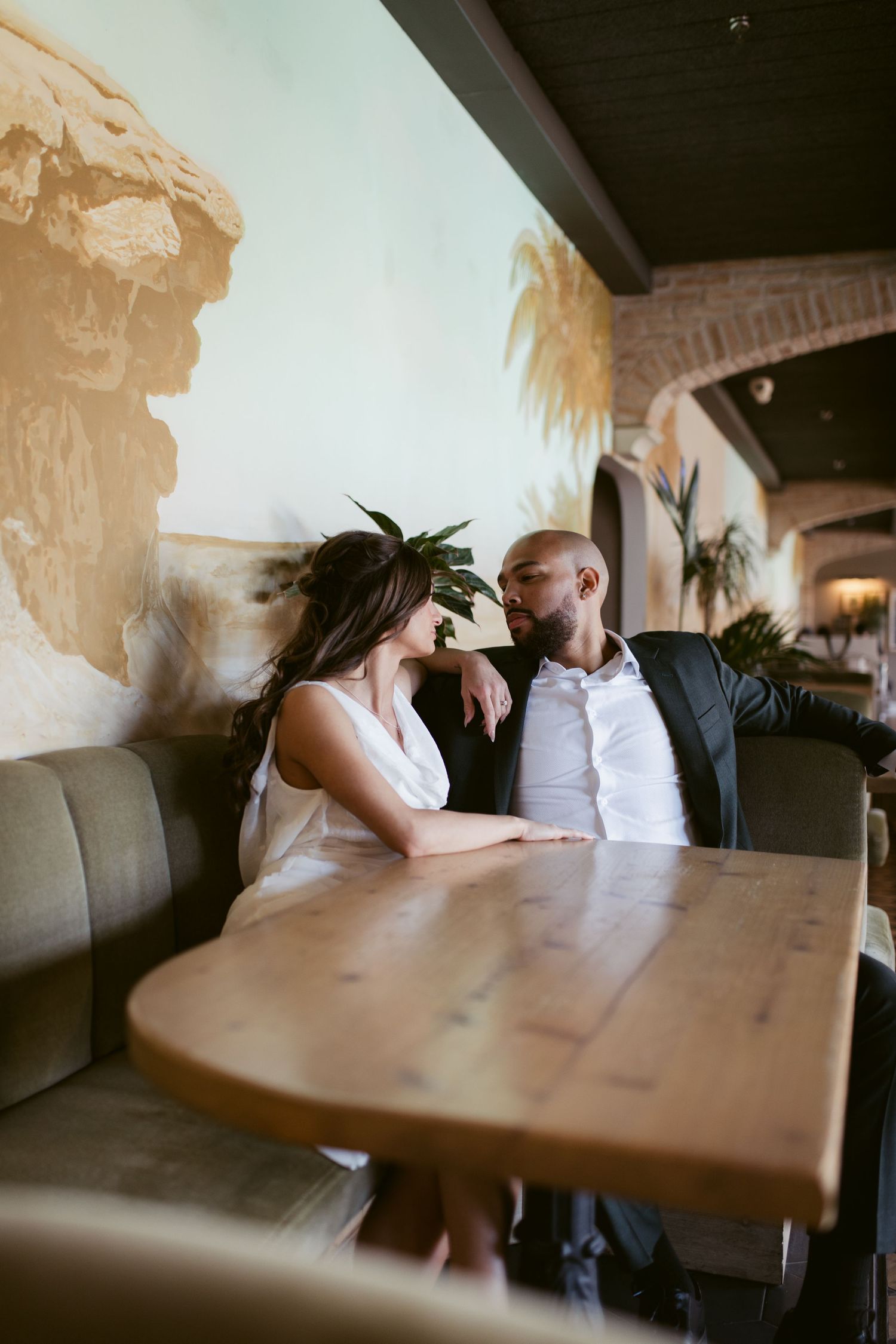 A couple sharing a romantic moment at a wooden table in a restaurant booth.