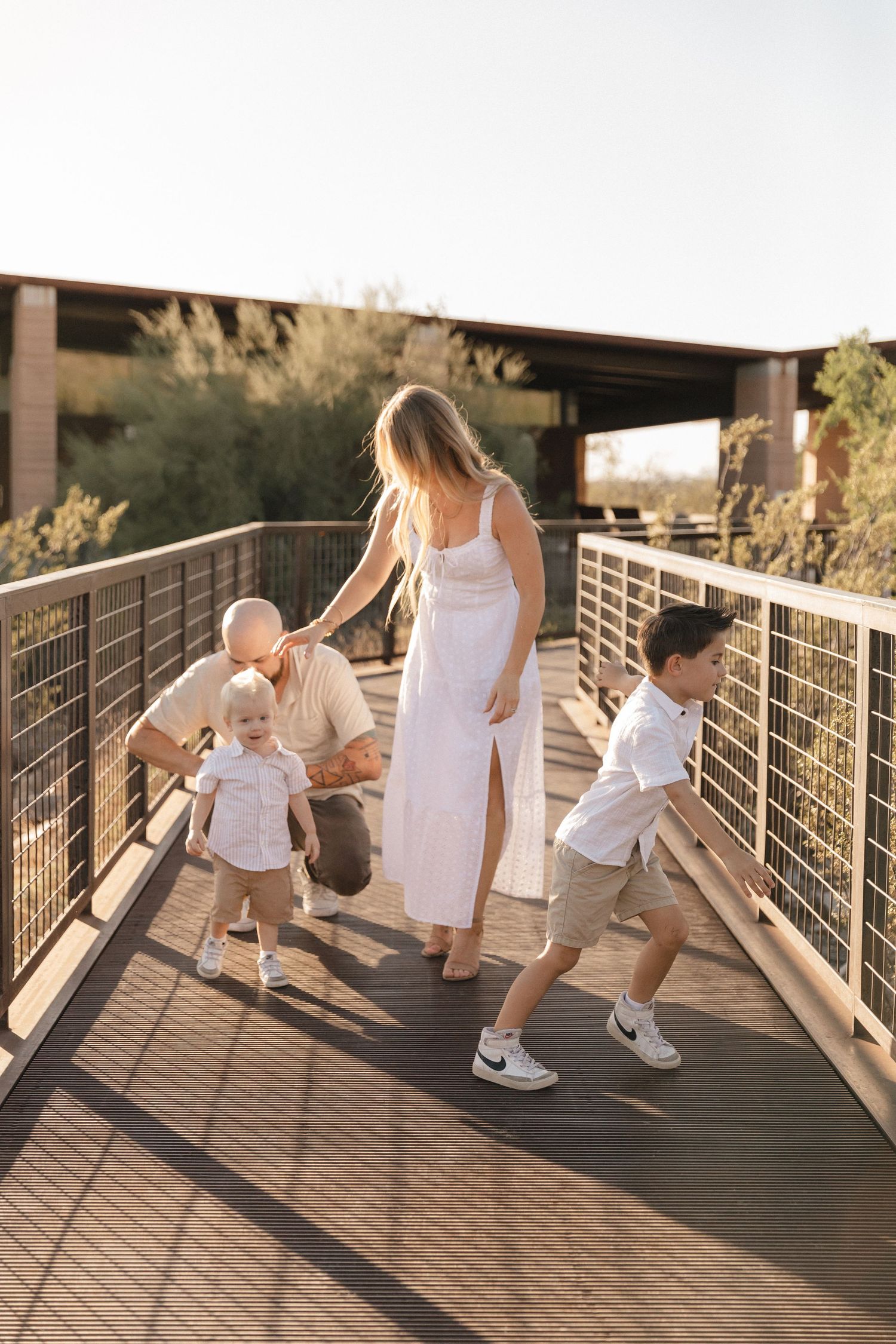 A series of connected photos showing a parent and toddler walking and playing together on a wooden bridge at sunset.
