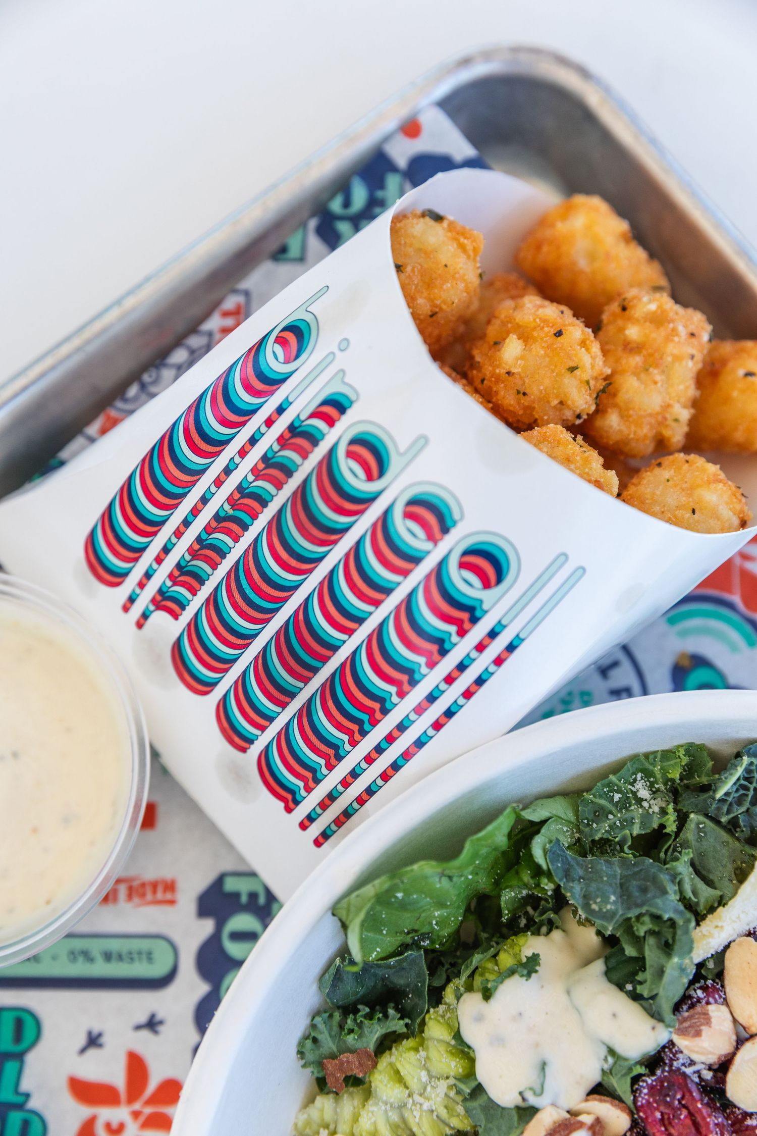 Crispy tater tots and salad served with retro-styled restaurant branding.