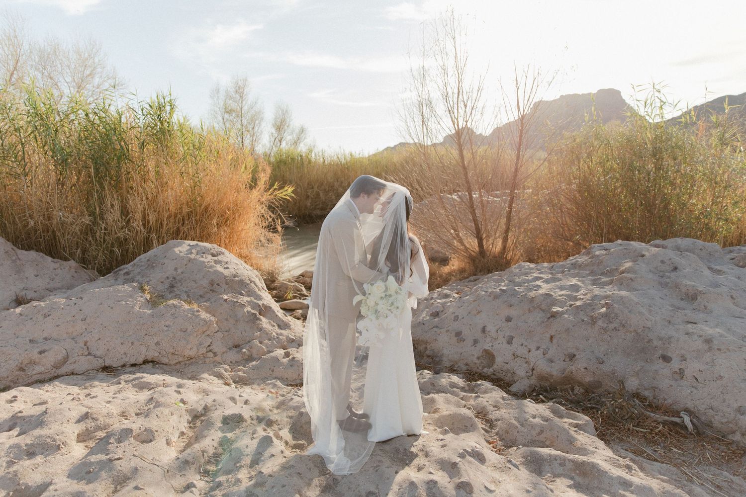 Wedding dress flowing in the breeze against a desert mountain landscape at golden hour.