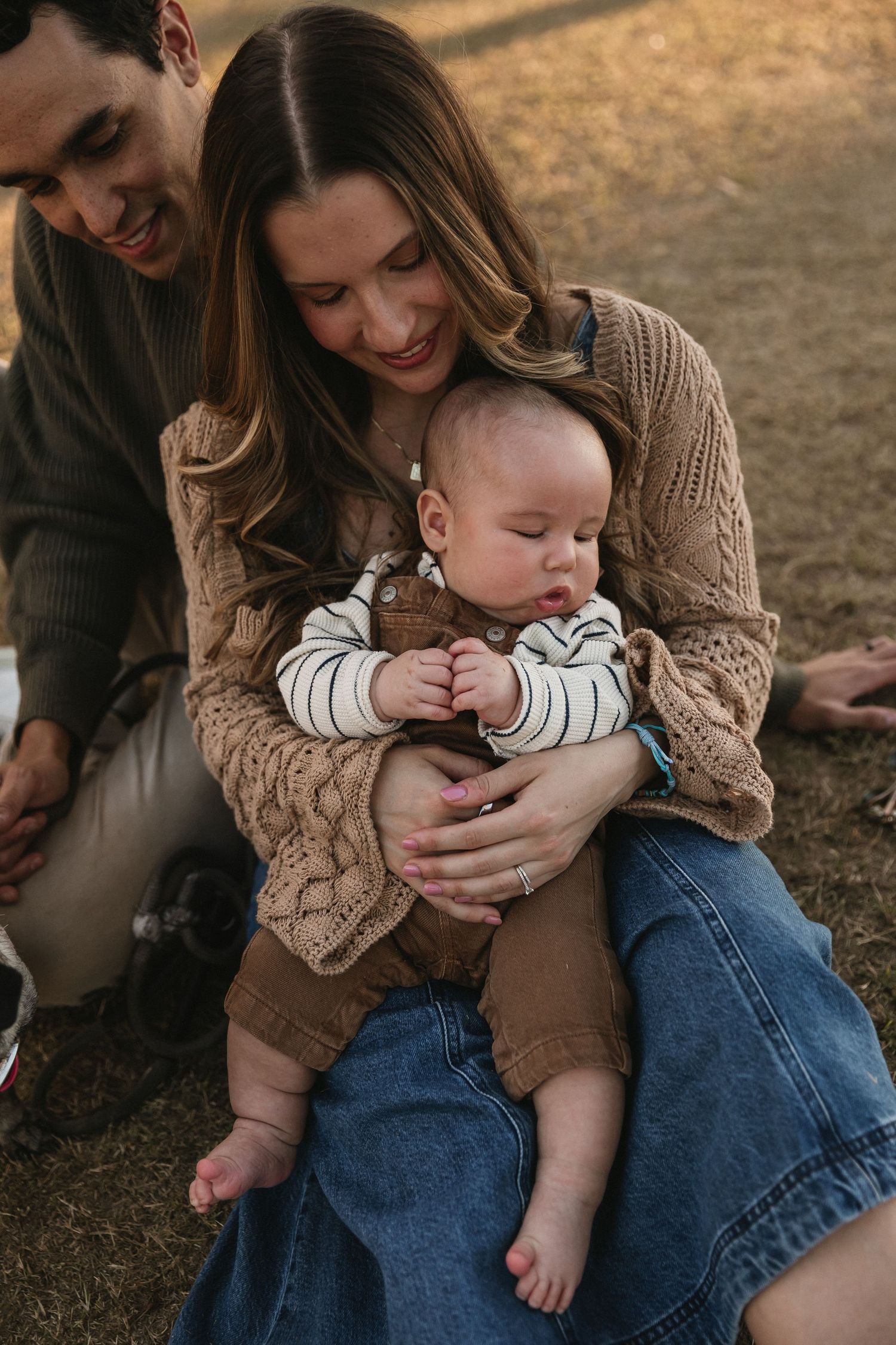 A family shares tender moments together outdoors during a casual photoshoot at golden hour.