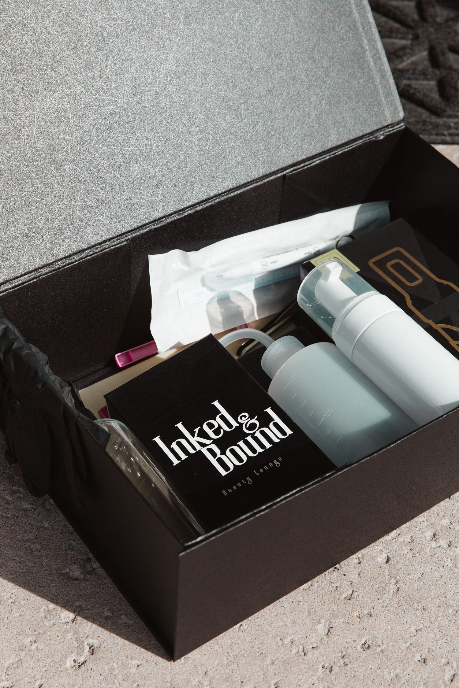 Open black box containing Inked & Bound branded products and supplies.