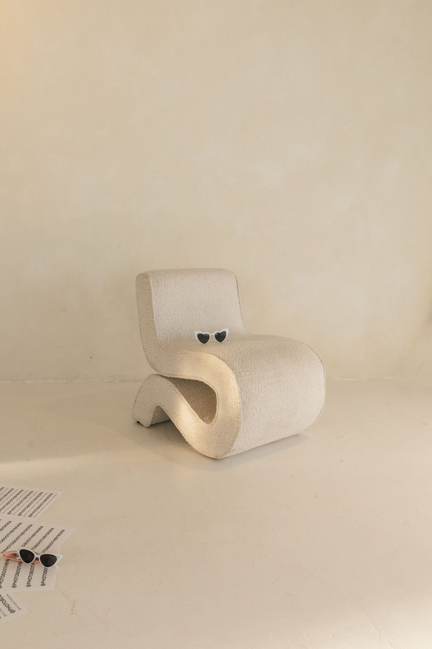 Modern curved white lounge chair with minimalist design against neutral beige background.