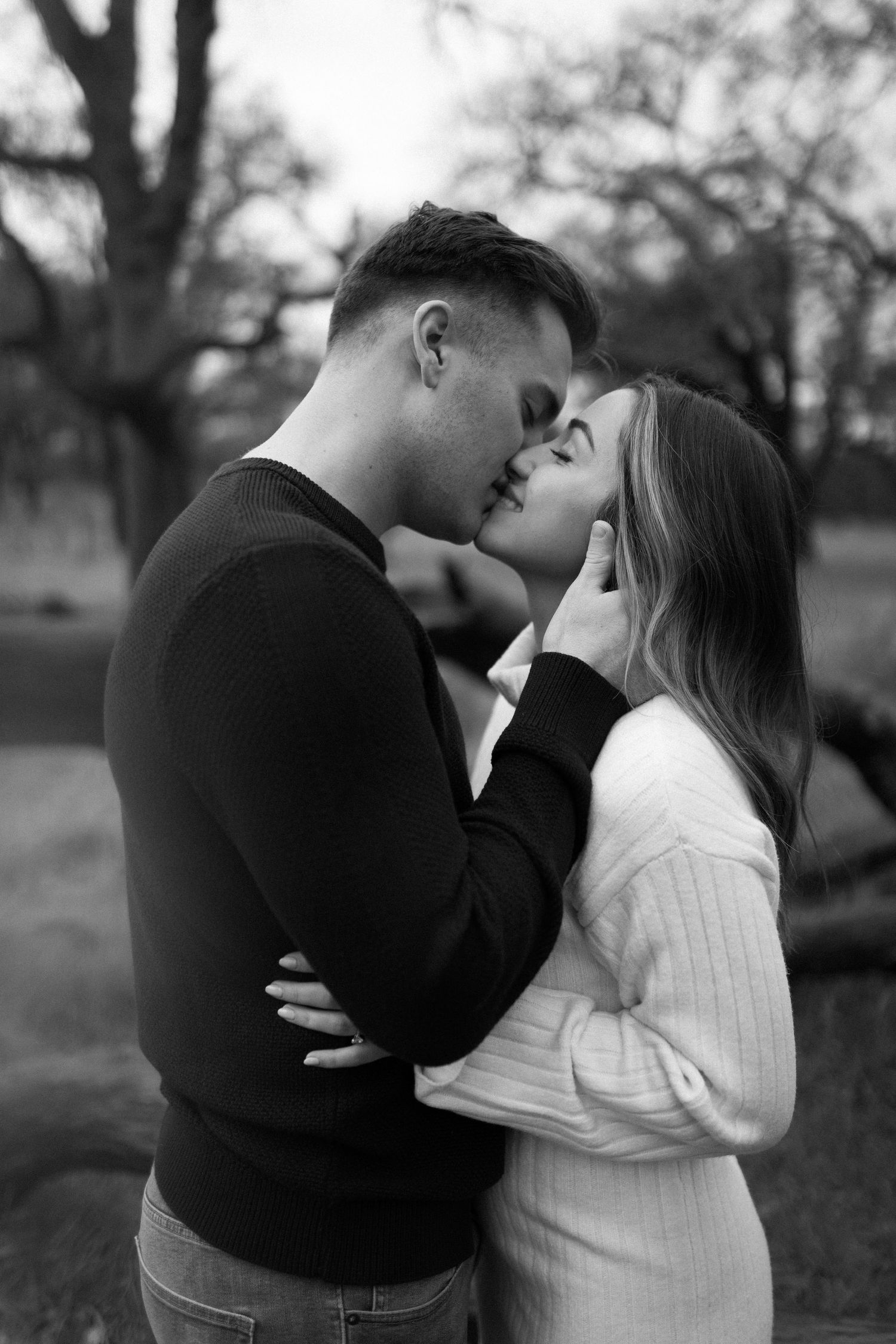 Black and white portrait of couple sharing an intimate moment outdoors.