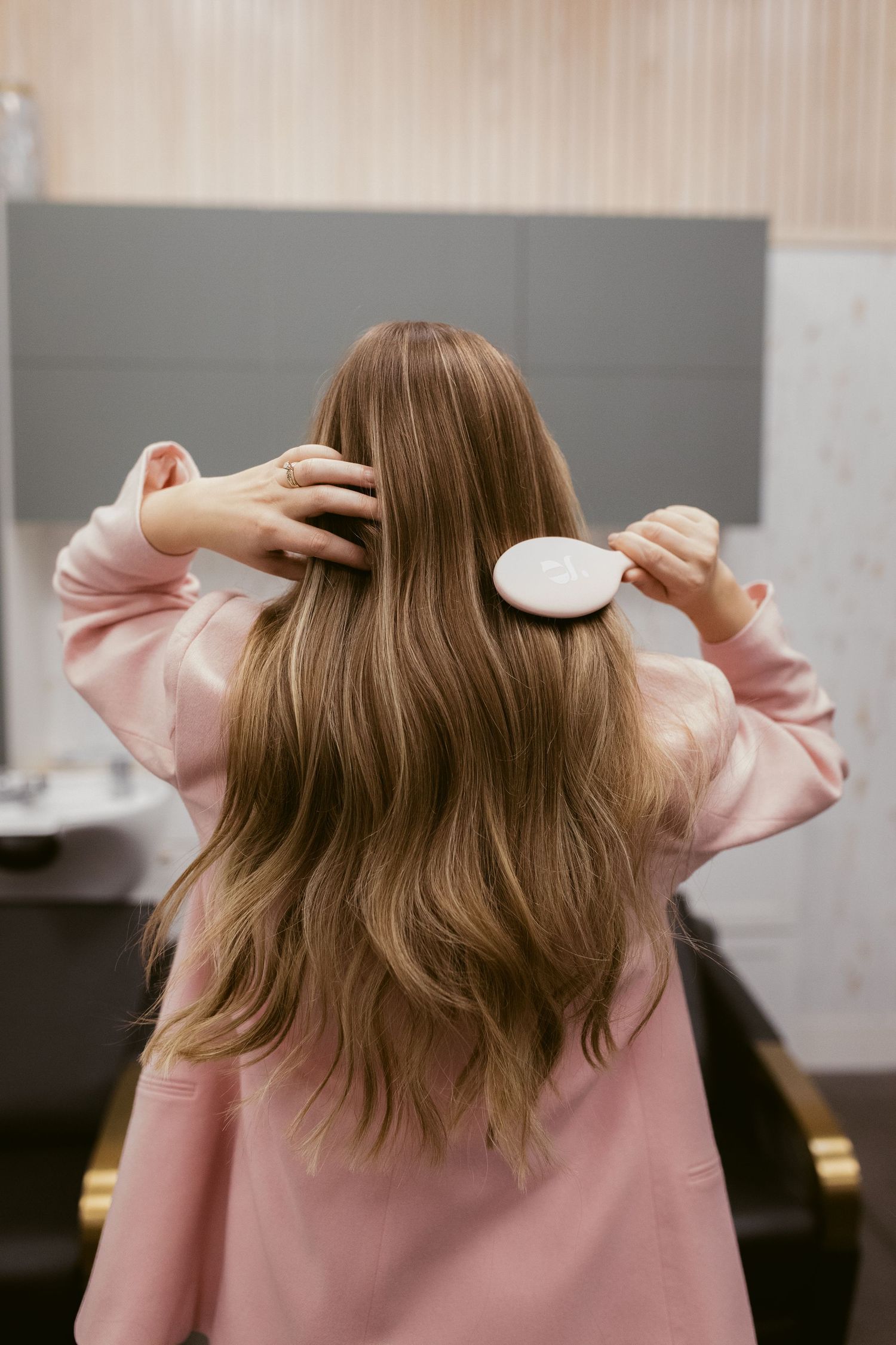 A person wearing a pink sweater makes a series of playful poses and arm movements in a sequence of candid shots.