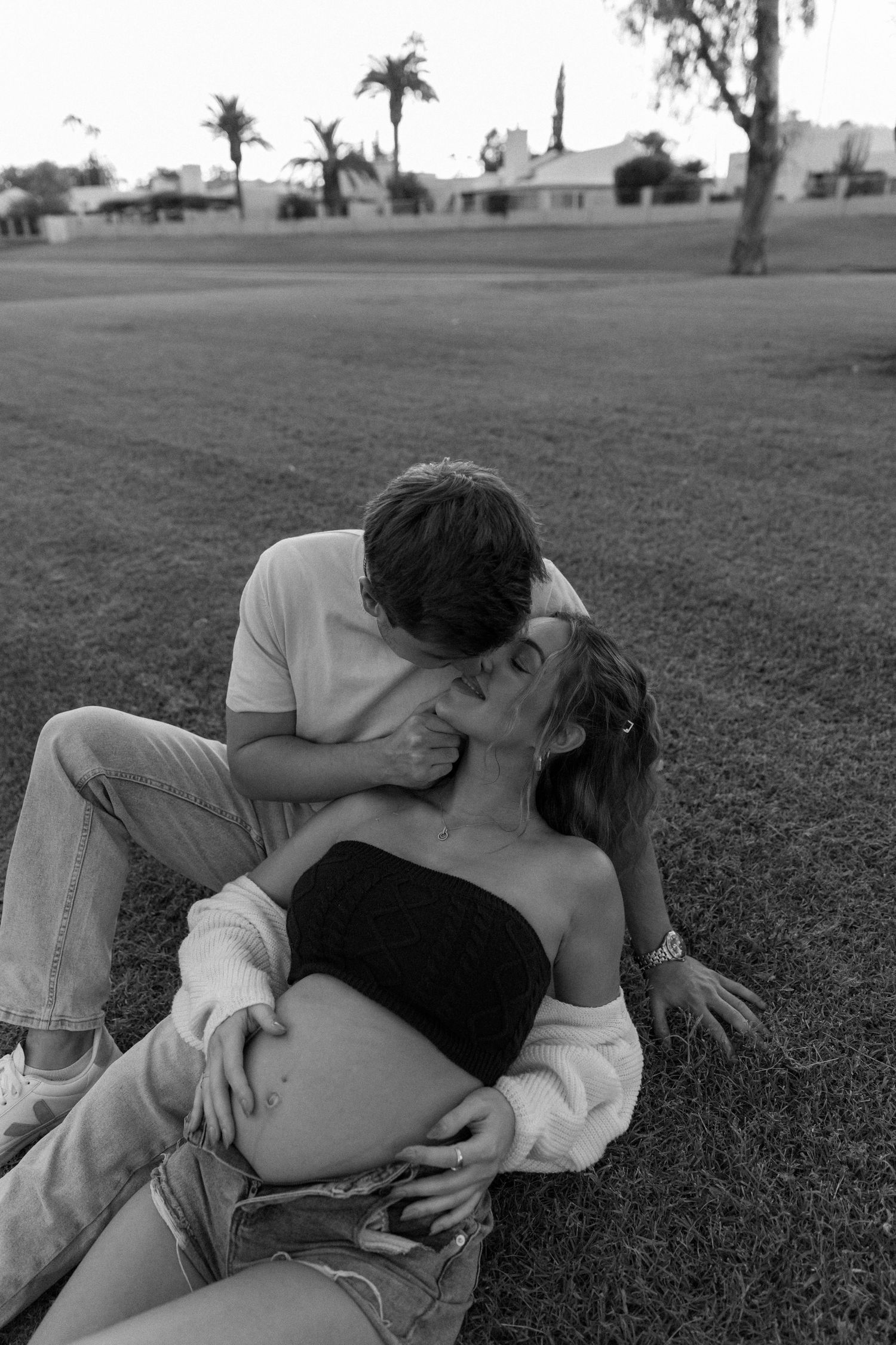 A couple lying together intimately on grass in a series of black and white romantic photographs.