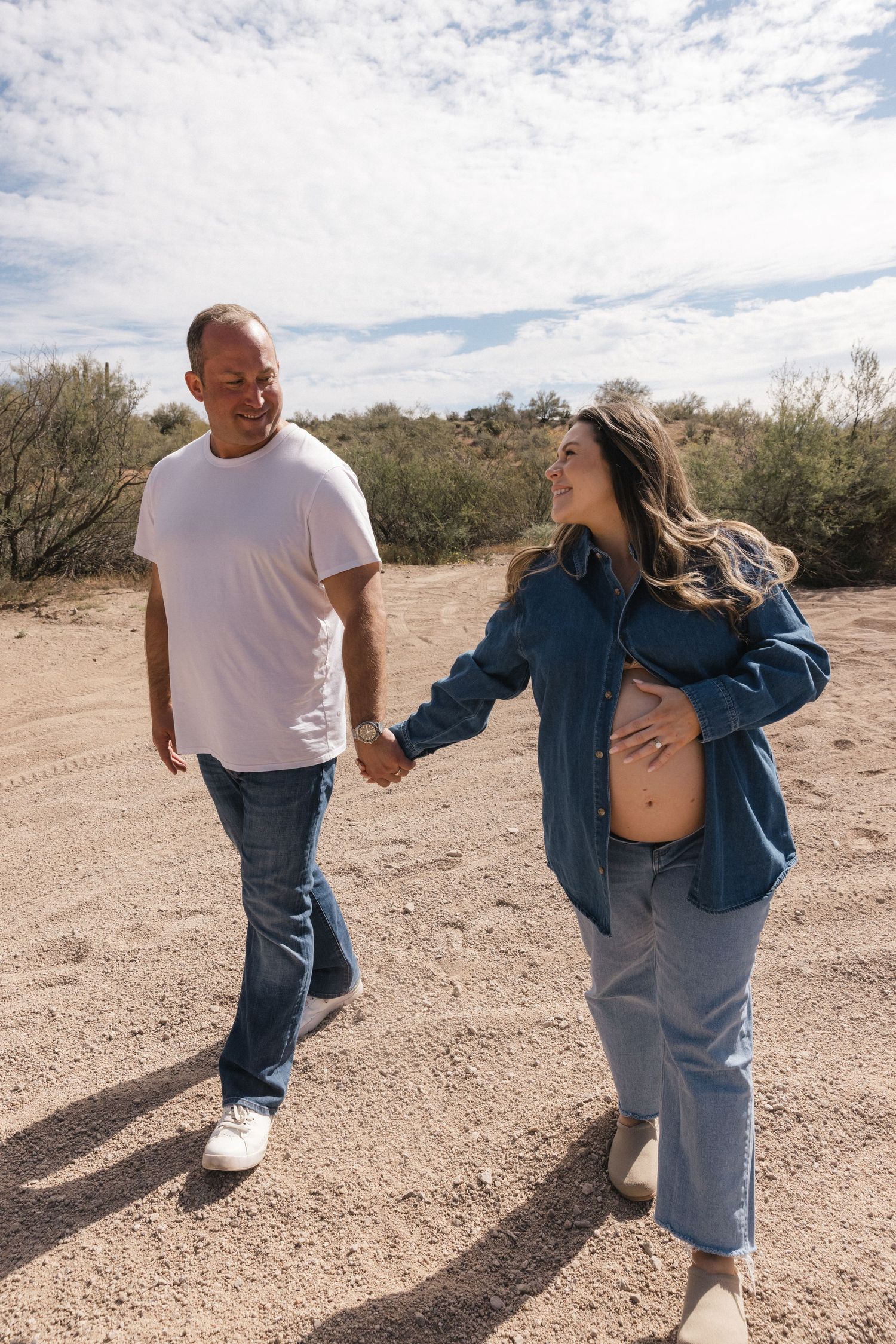 A couple dances playfully in the desert, shown in a sequence of candid movement shots against a cloudy sky.