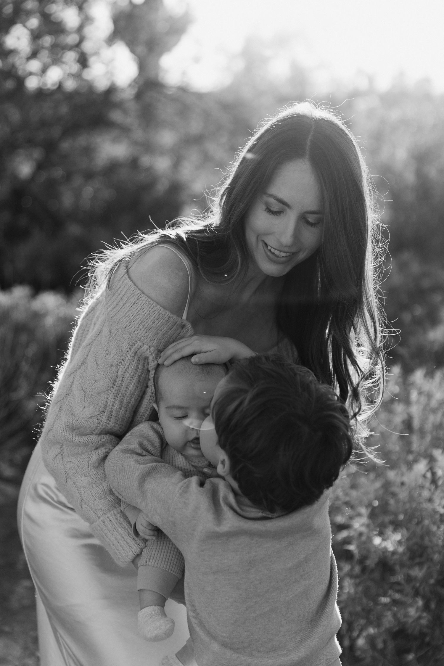A couple shares tender moments in a sunlit meadow during a romantic black and white photo session.