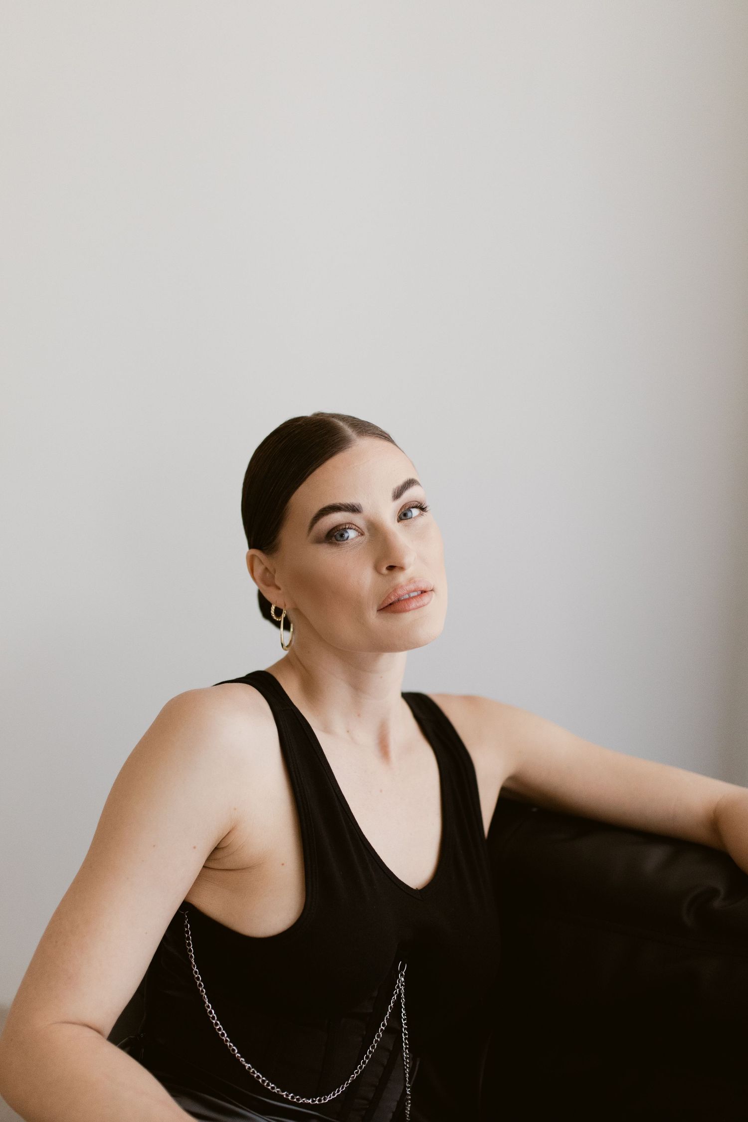 Portrait of model in sleek black dress against minimal white background.