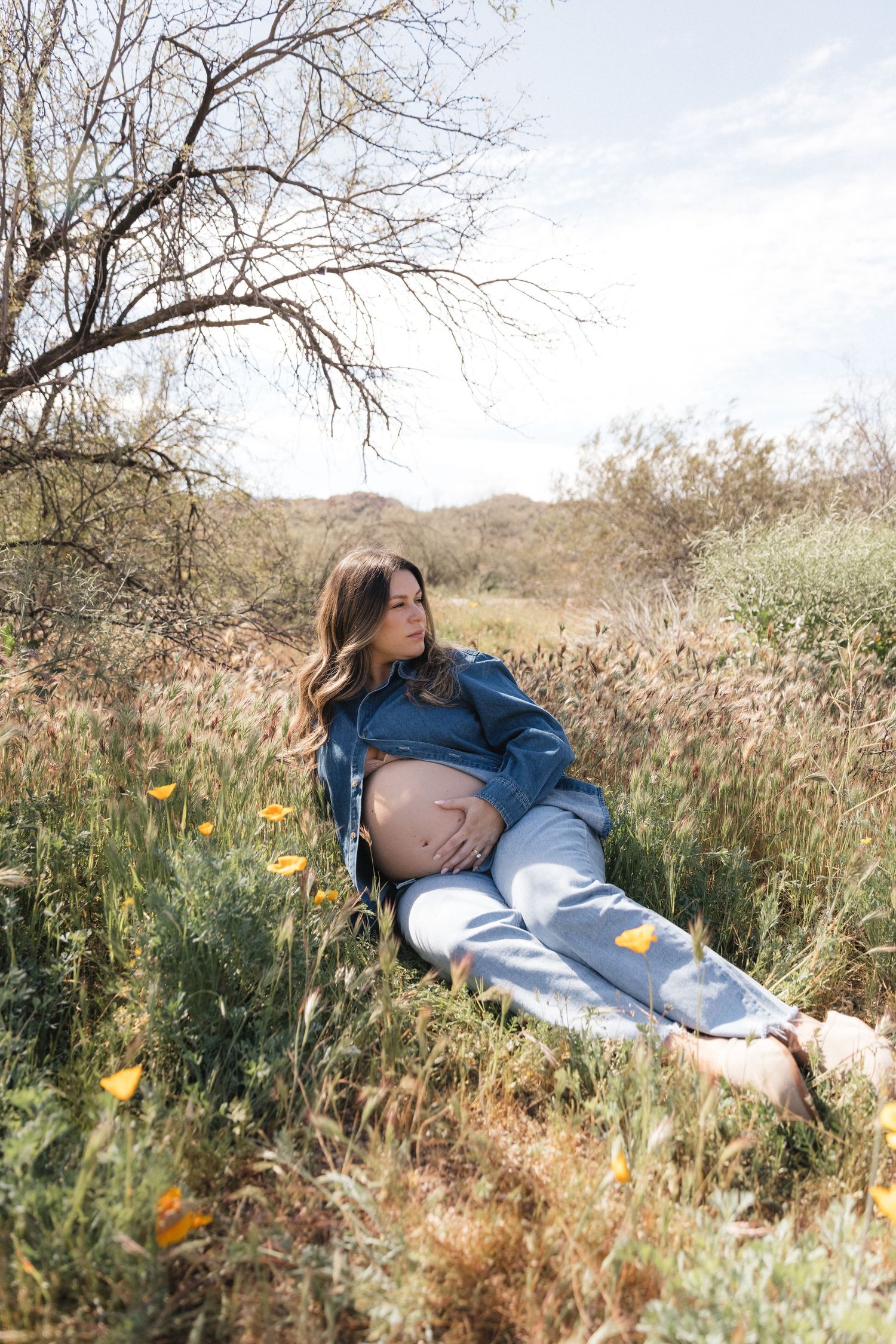 Someone wearing a denim jacket lies peacefully in a wildflower meadow during autumn.