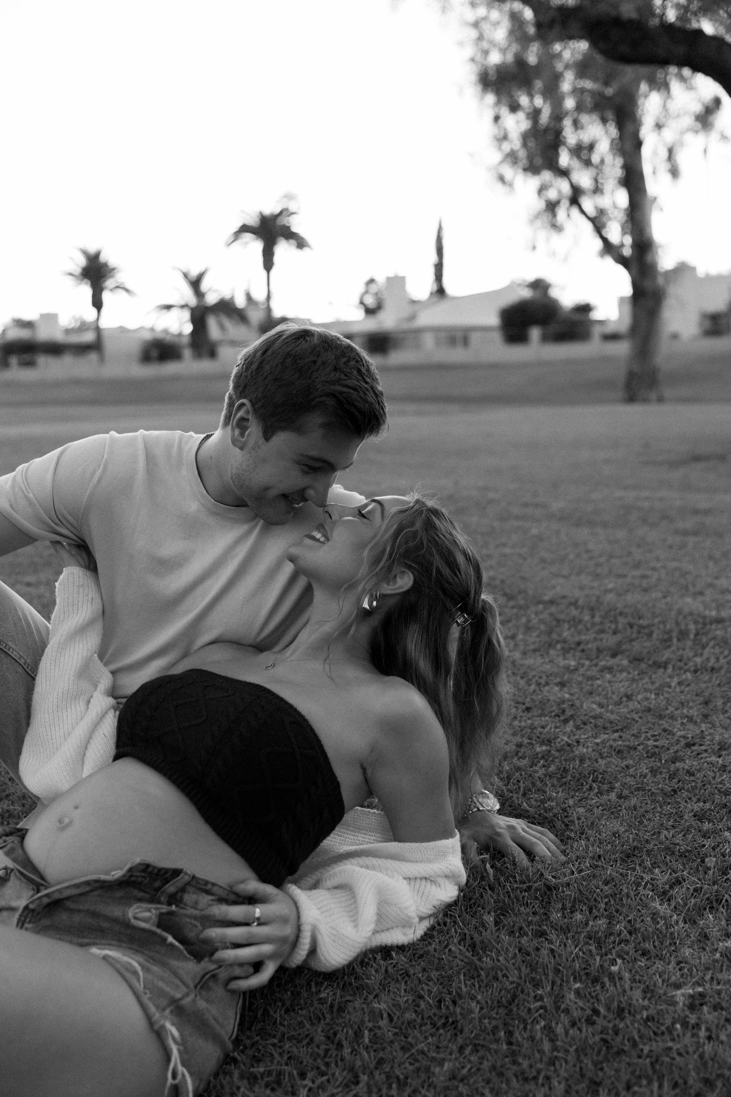 A romantic black and white photo series of a couple lying in grass together.