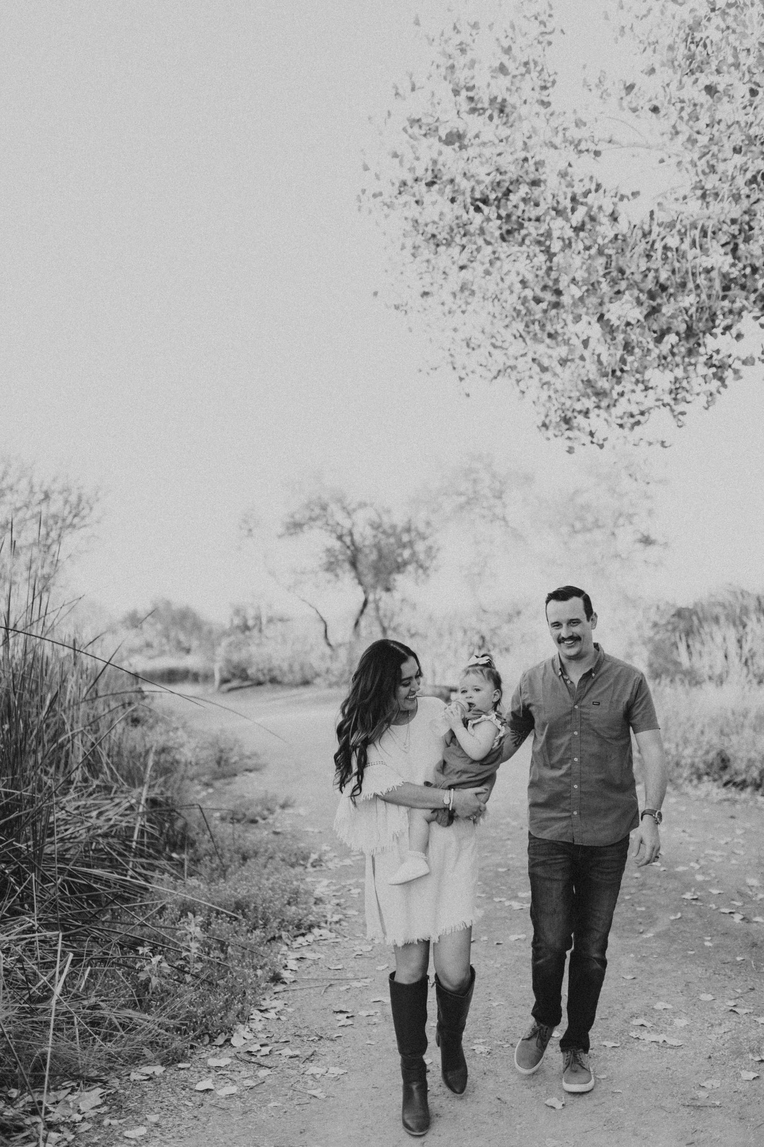 Black and white family portrait walking together on nature trail.