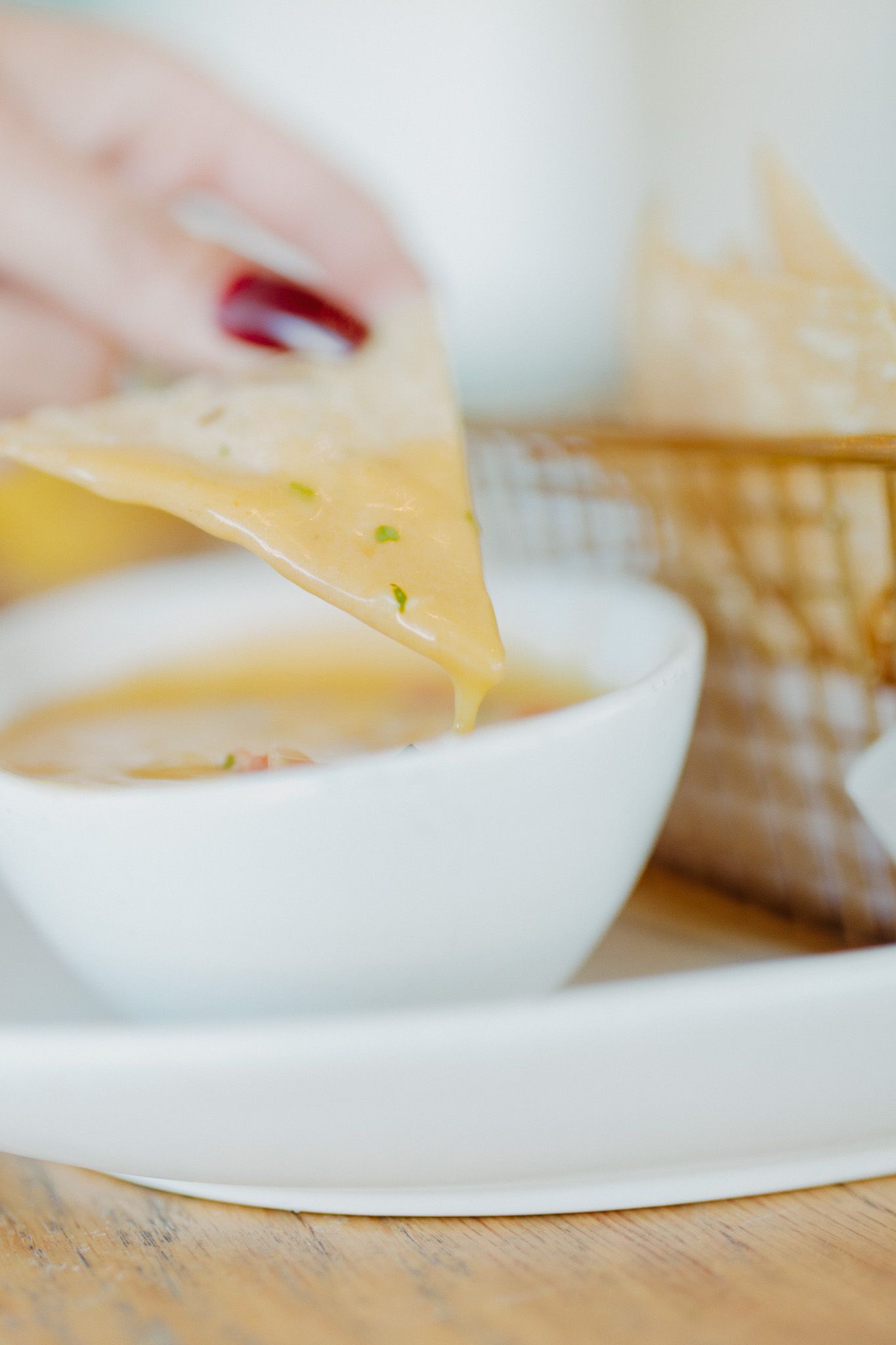 Close-up of cheese being served from a white bowl on a wooden table.