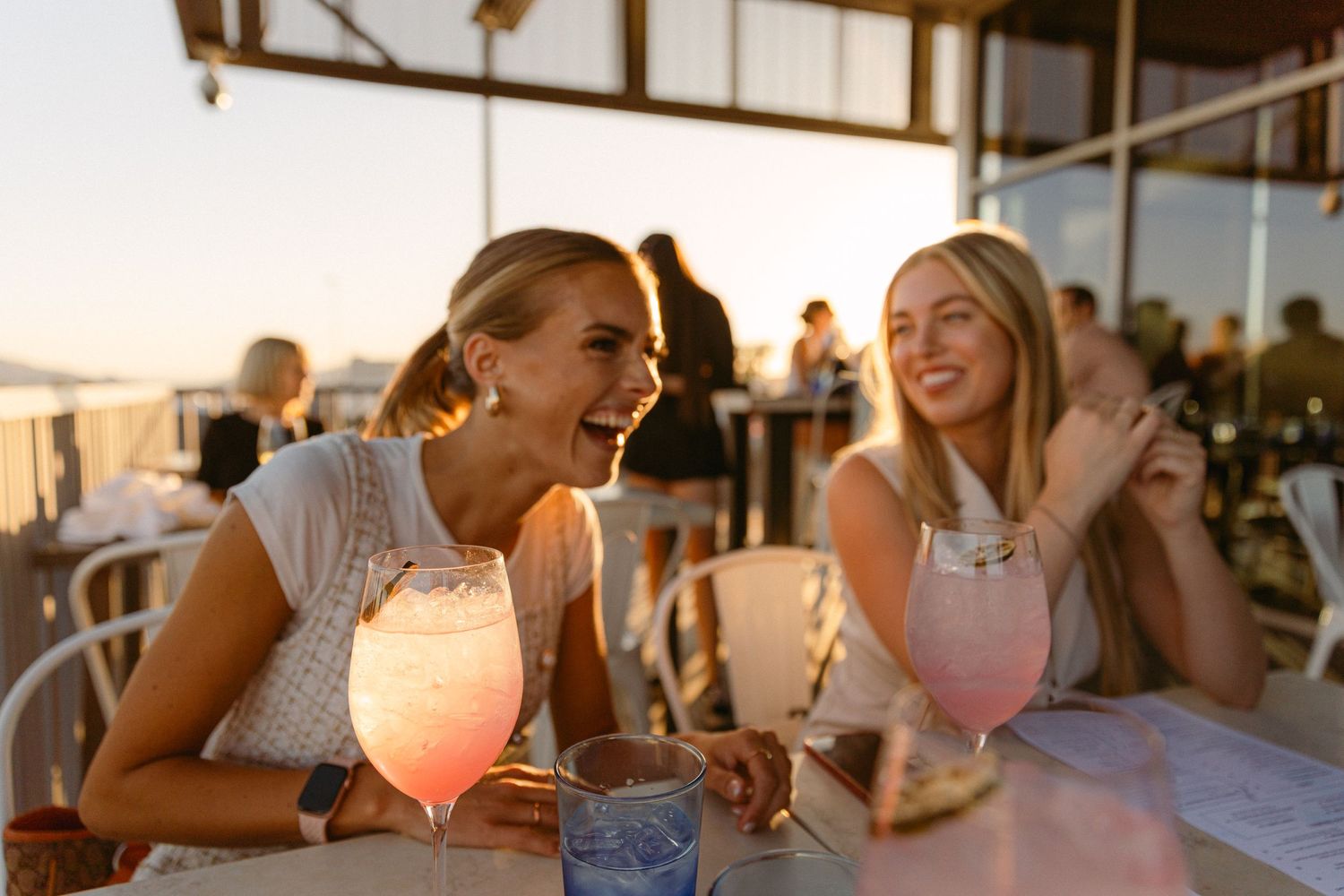 Sunset drinks on outdoor patio with pink cocktails and summer atmosphere.