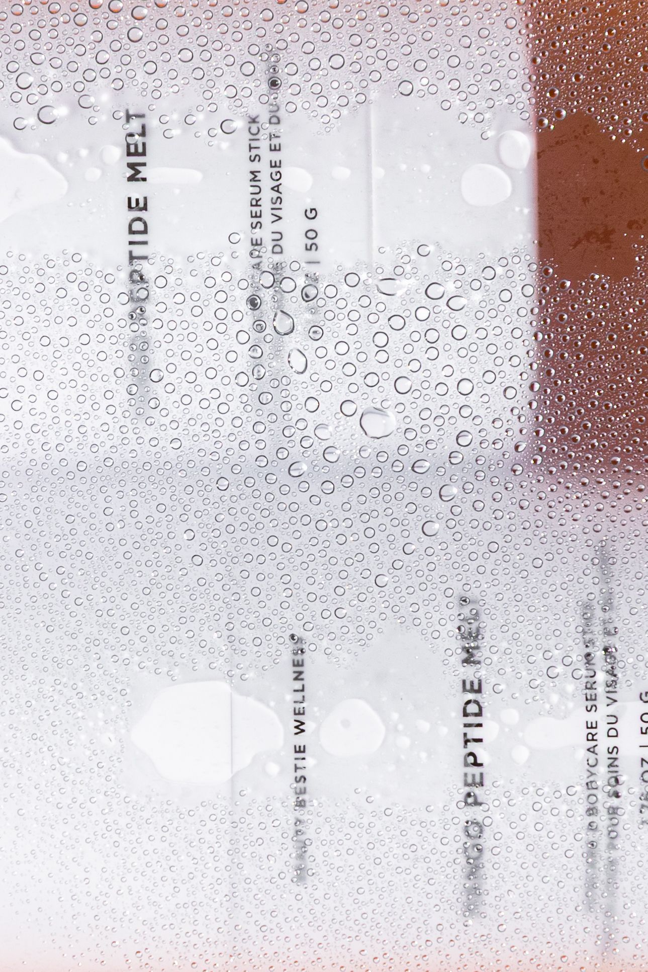 Water droplets and condensation on a clear glass or plastic surface create a dreamy, abstract texture pattern.