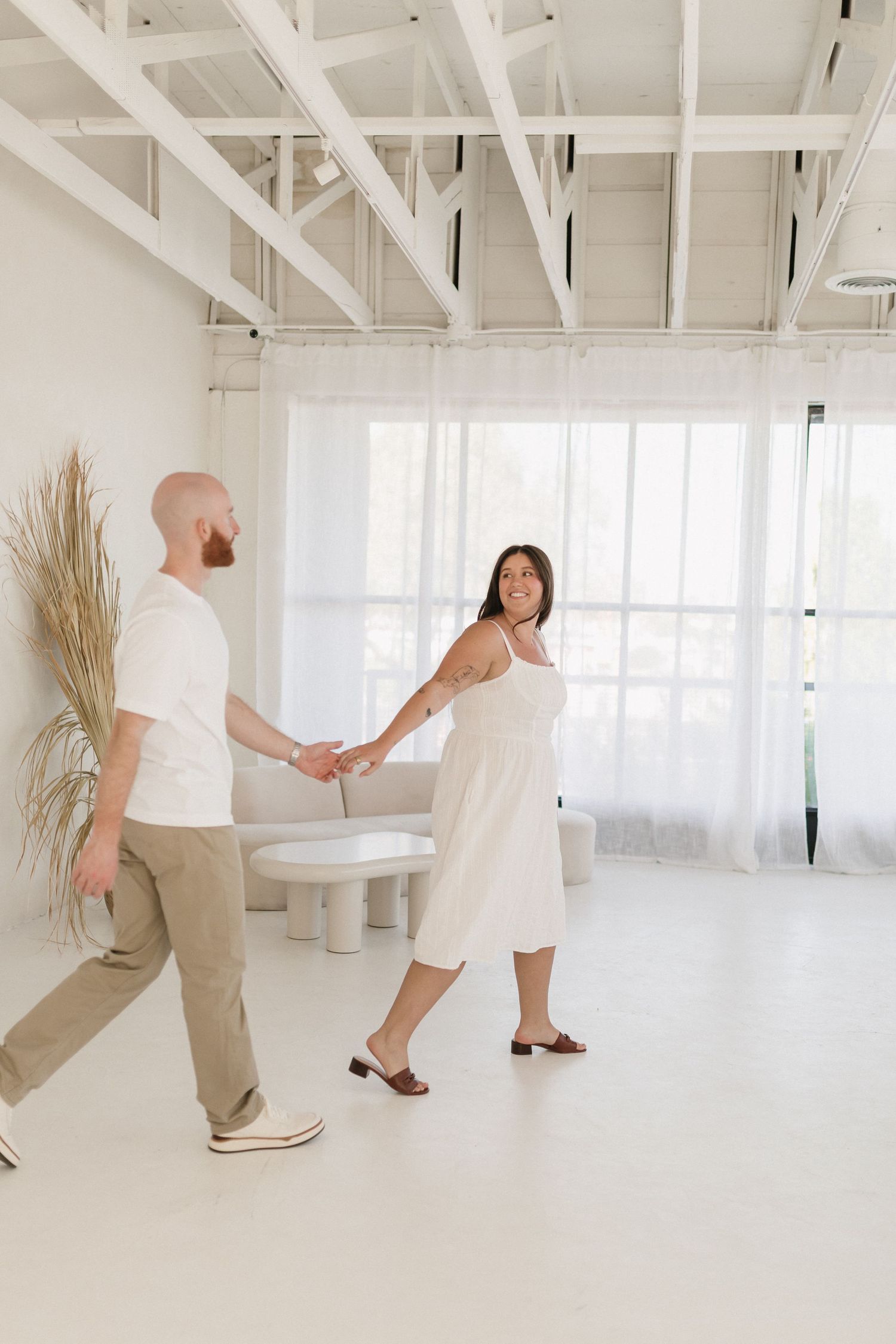 Three images of movement in all white studio space with dried pampas grass decor and minimal furniture.