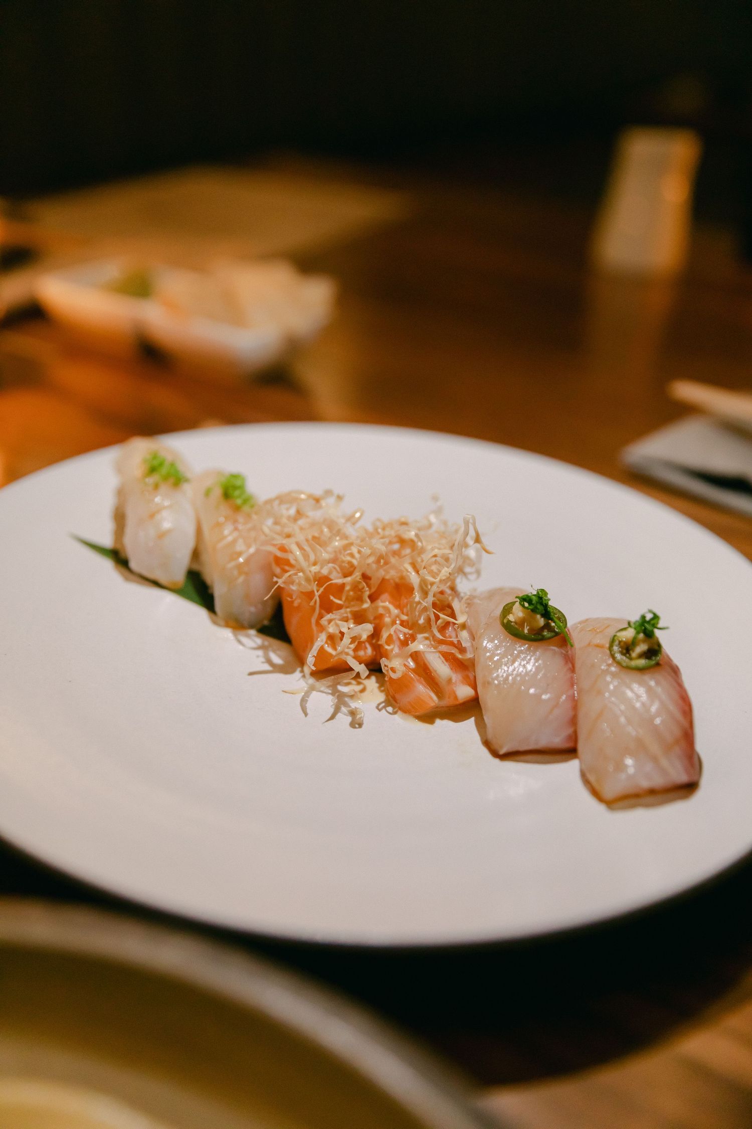Elegant plating of raw fish sashimi garnished with microgreens on white porcelain.