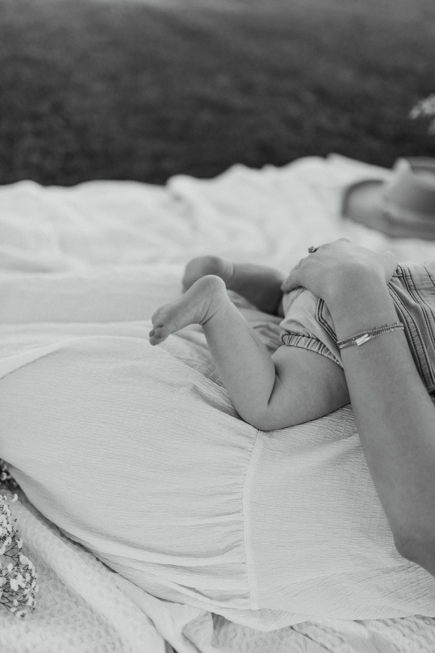 Black and white photo of small feet resting on white fabric.