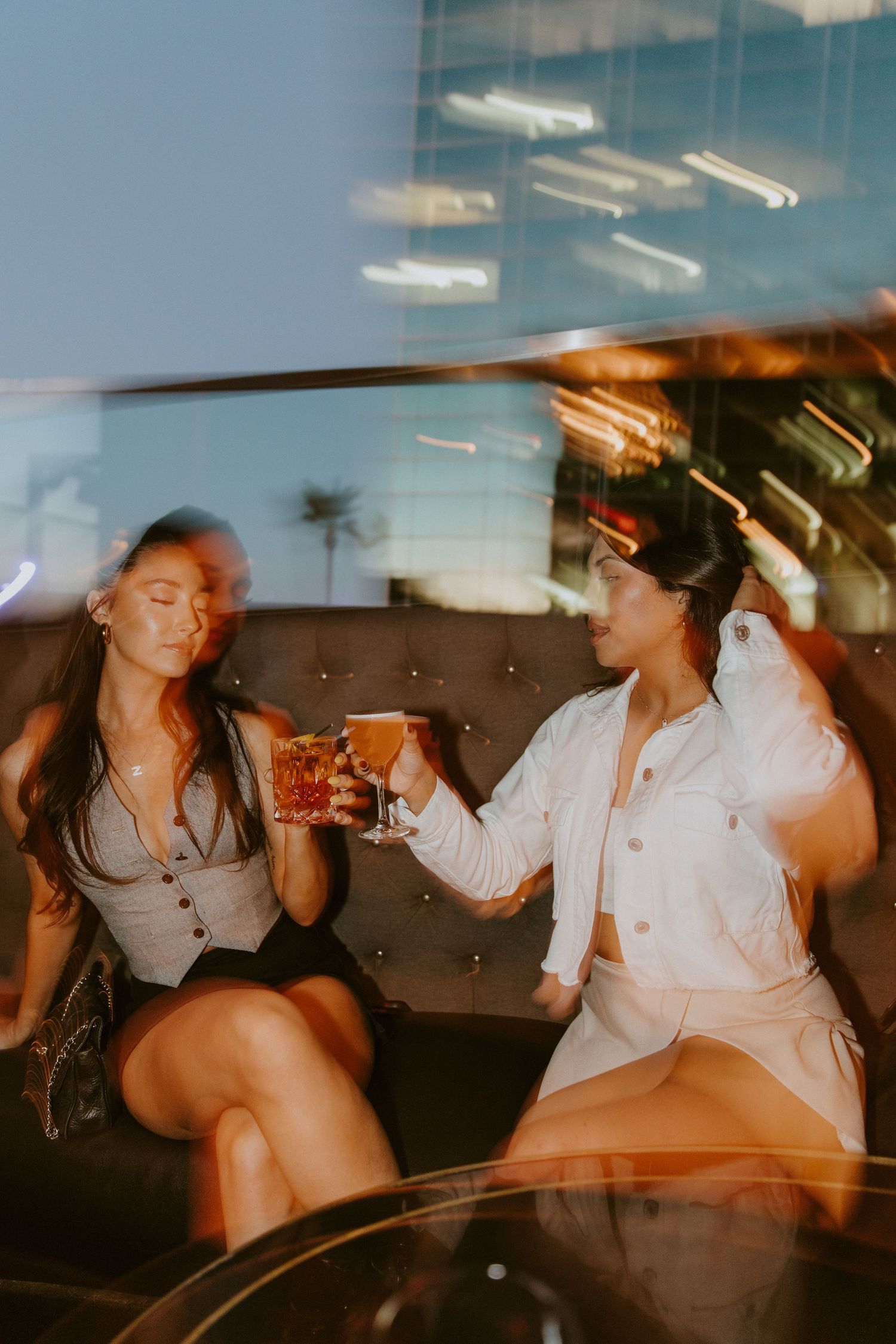Two glasses being toasted in the backseat of a car during sunset.
