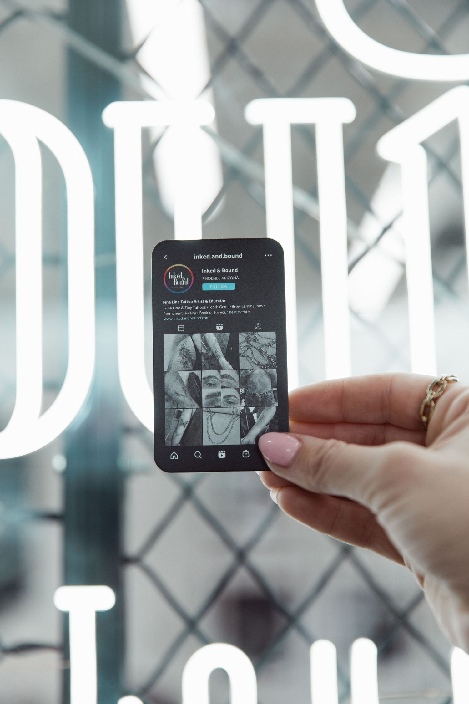 Hand holding phone displaying social media content against illuminated signage.
