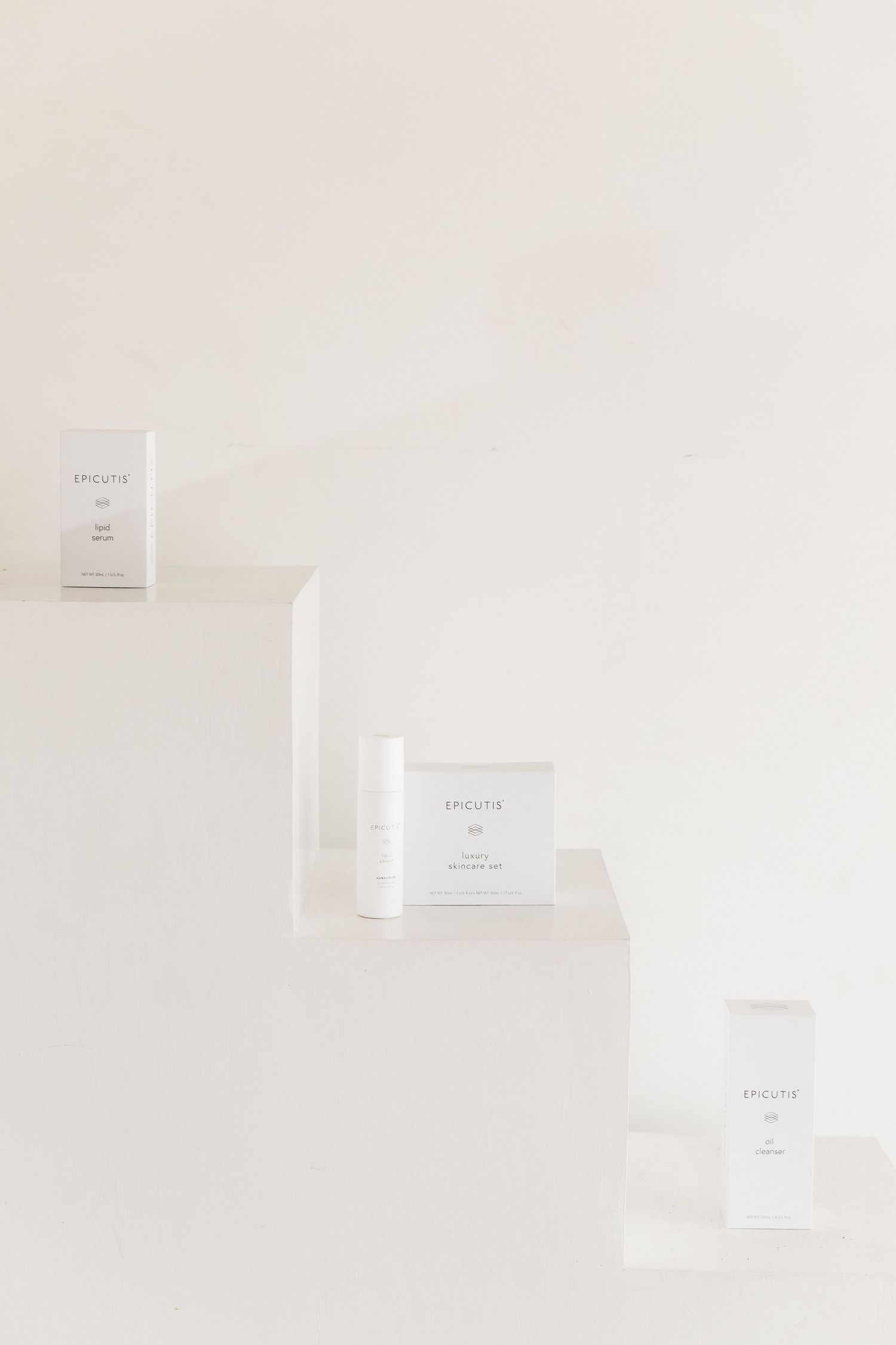 Minimalist white product packaging boxes arranged in a clean, monochromatic composition against a light background.