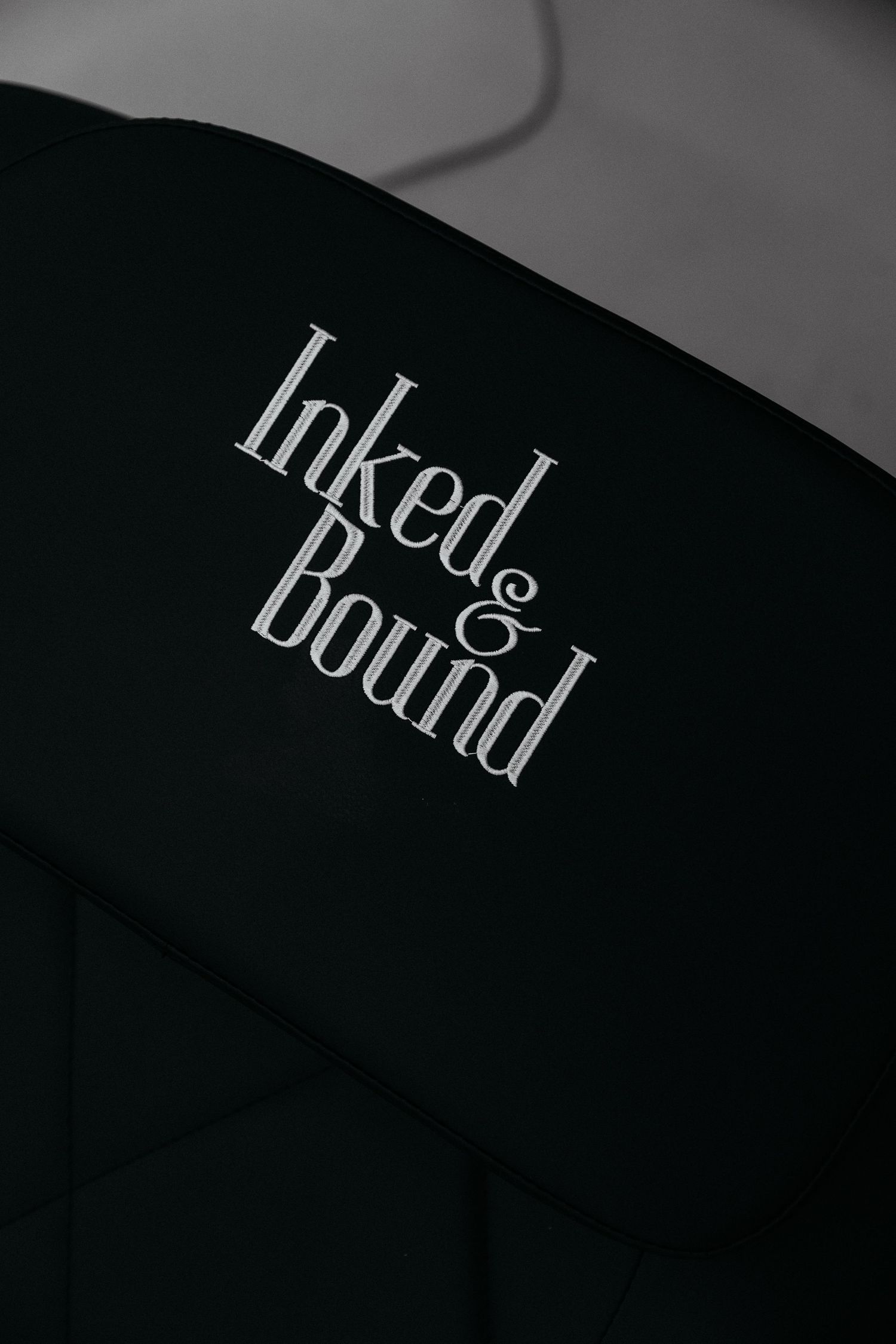 Black chair with 'Inked & Bound' logo embroidered in white text.