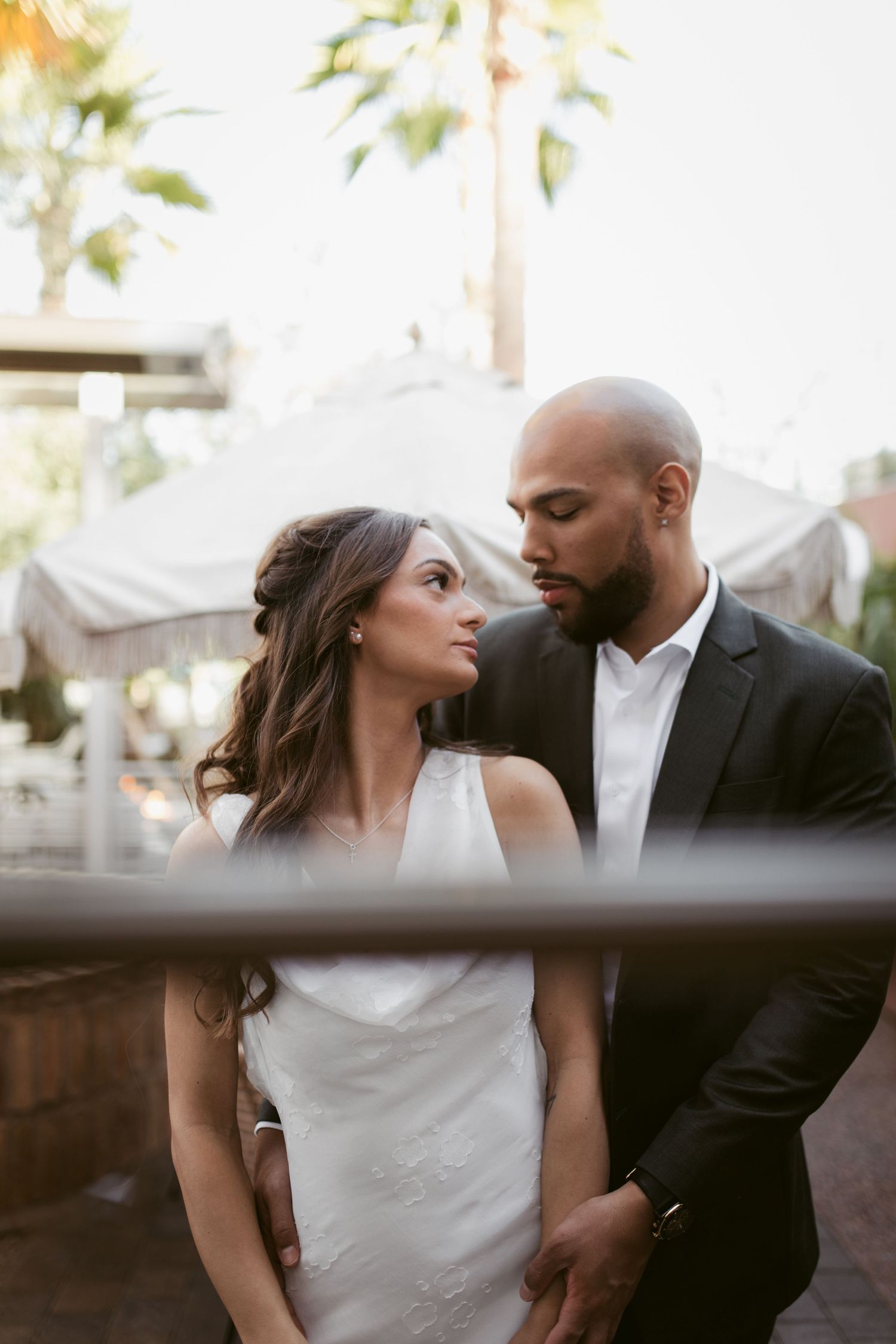 An elegant couple in wedding attire sharing an intimate moment in an outdoor setting.