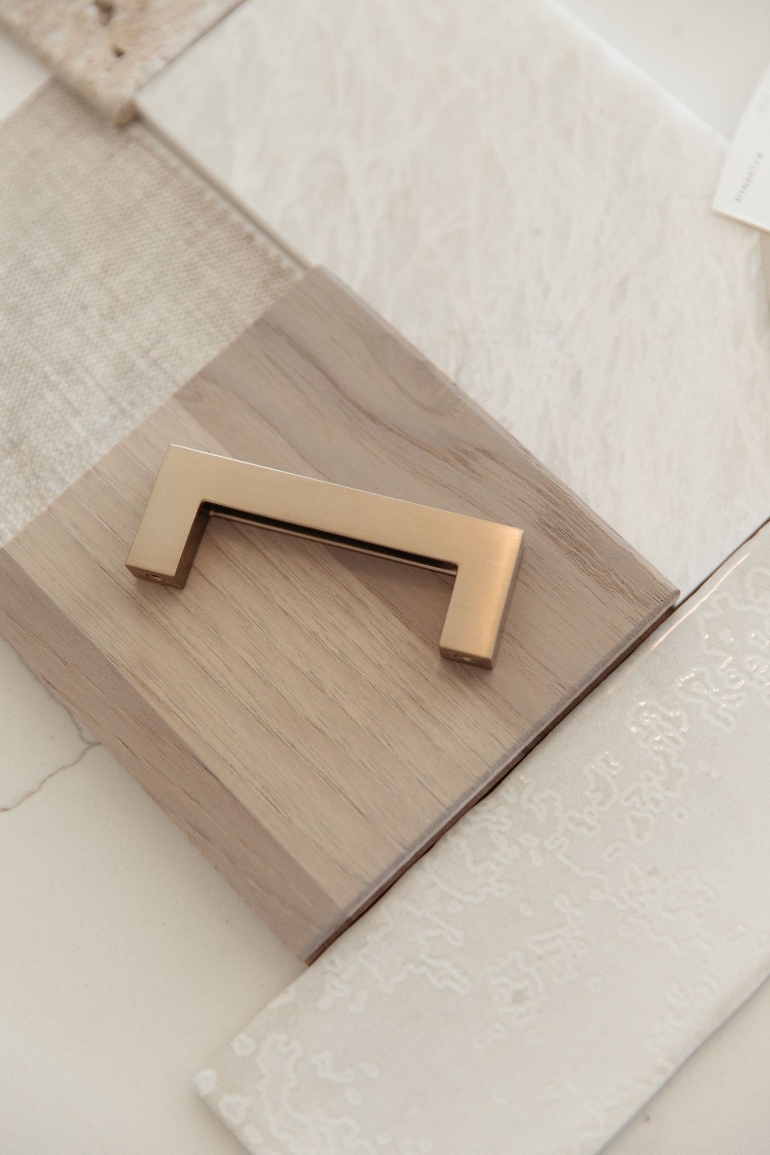 Close-up of modern gold cabinet handle on light wood sample.