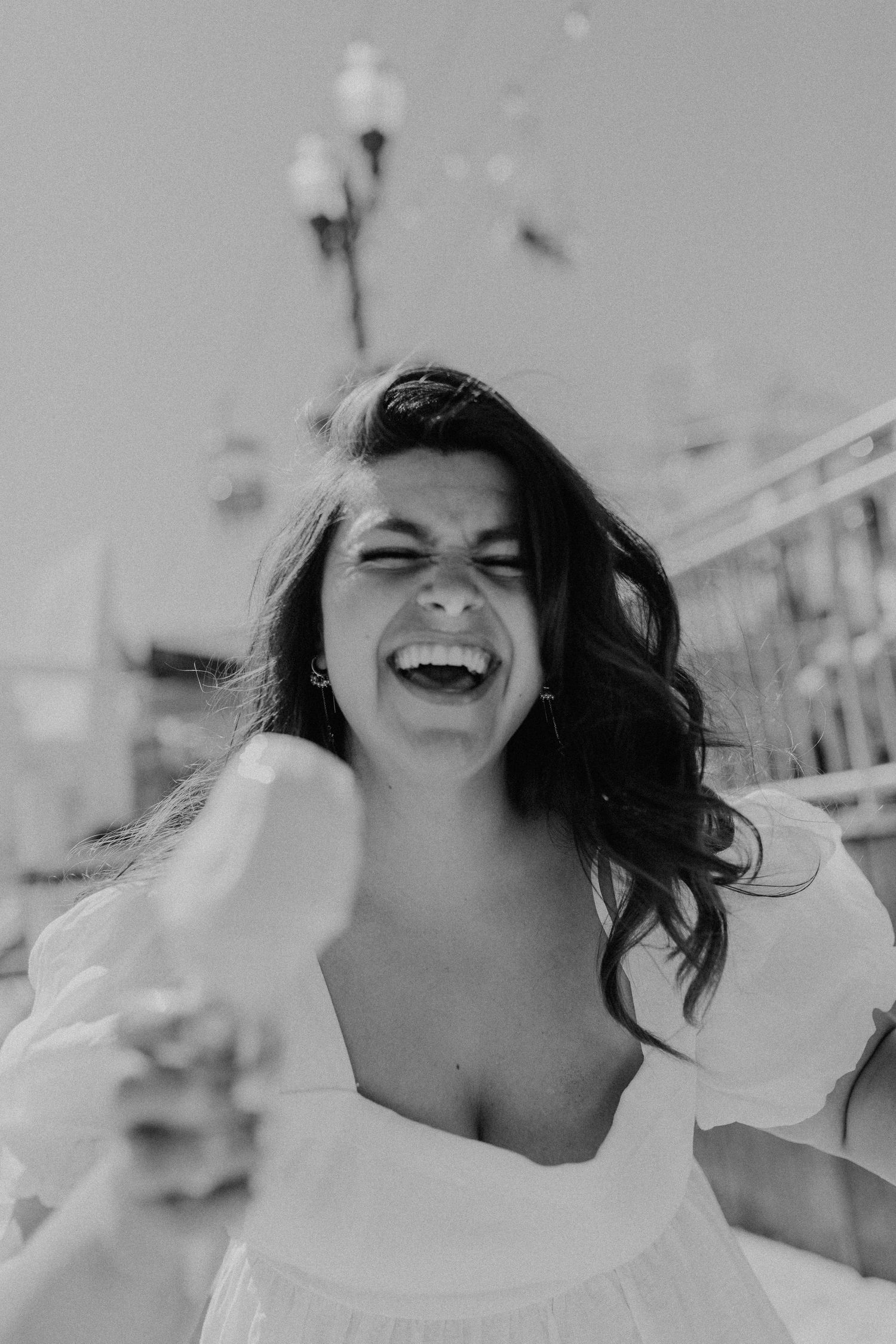 Black and white portrait capturing joyful laughter in bright sunlight.