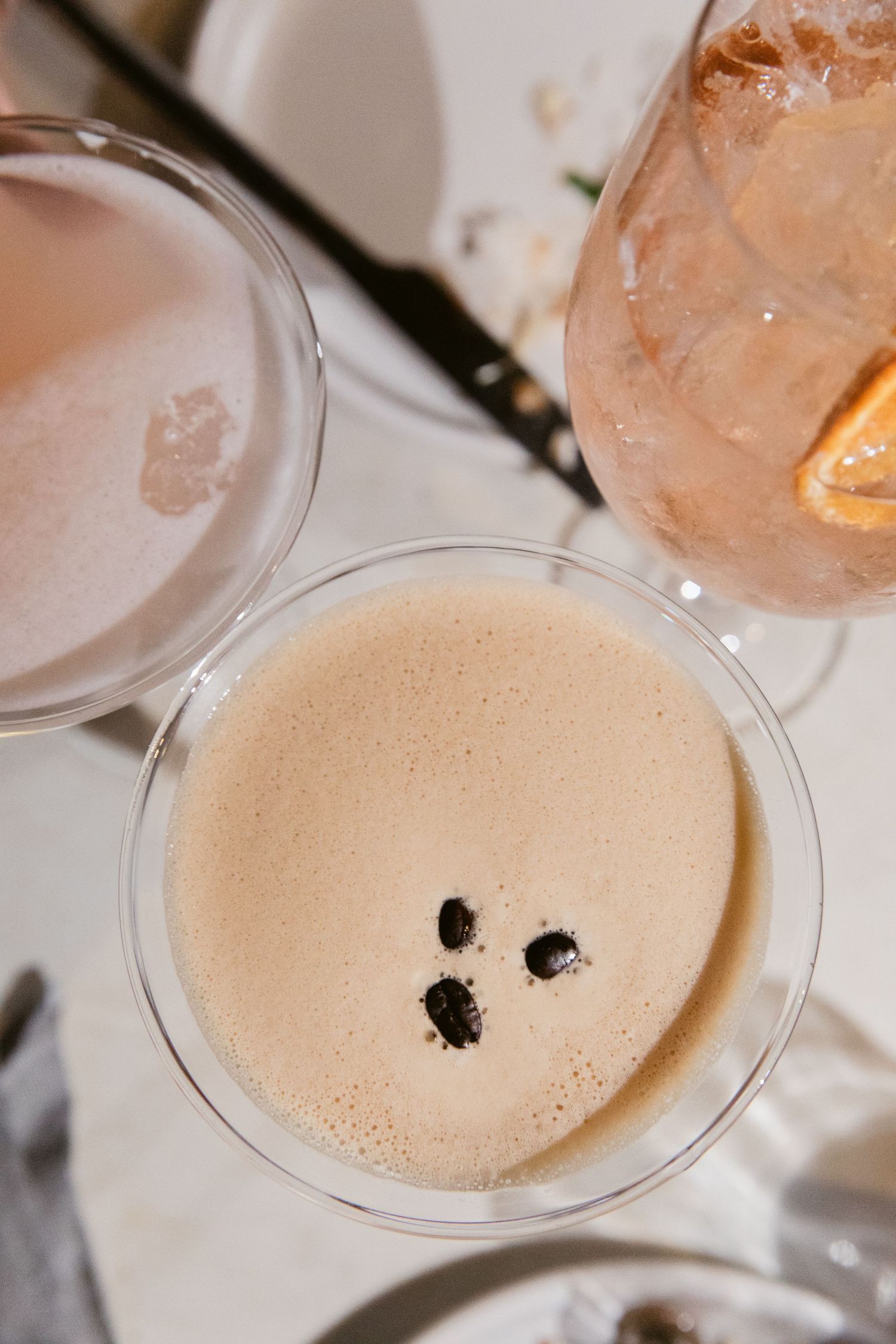 Overhead view of craft cocktails with one featuring coffee beans as garnish.