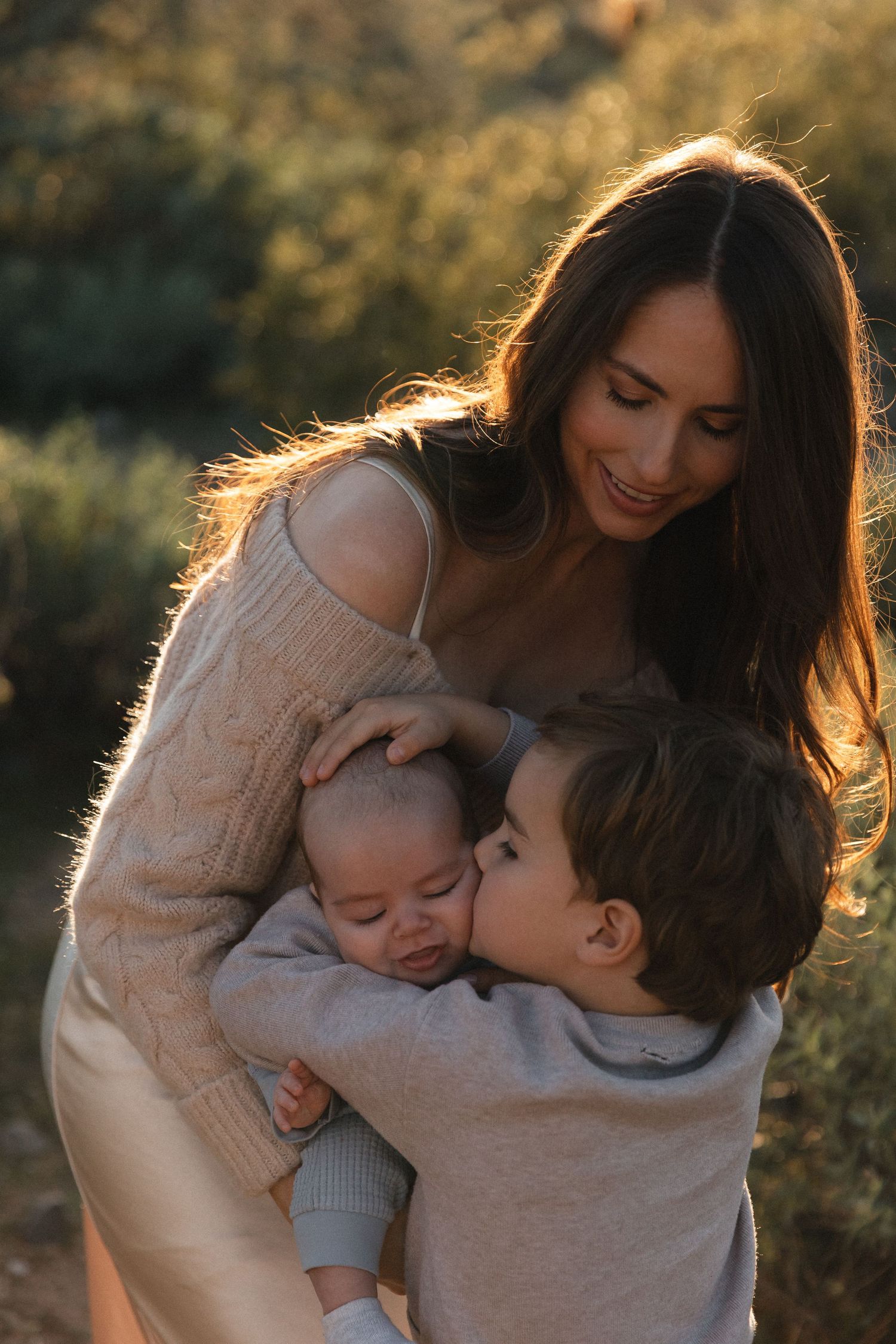 A tender family moment captured in golden sunlight as they share embraces and affection outdoors.
