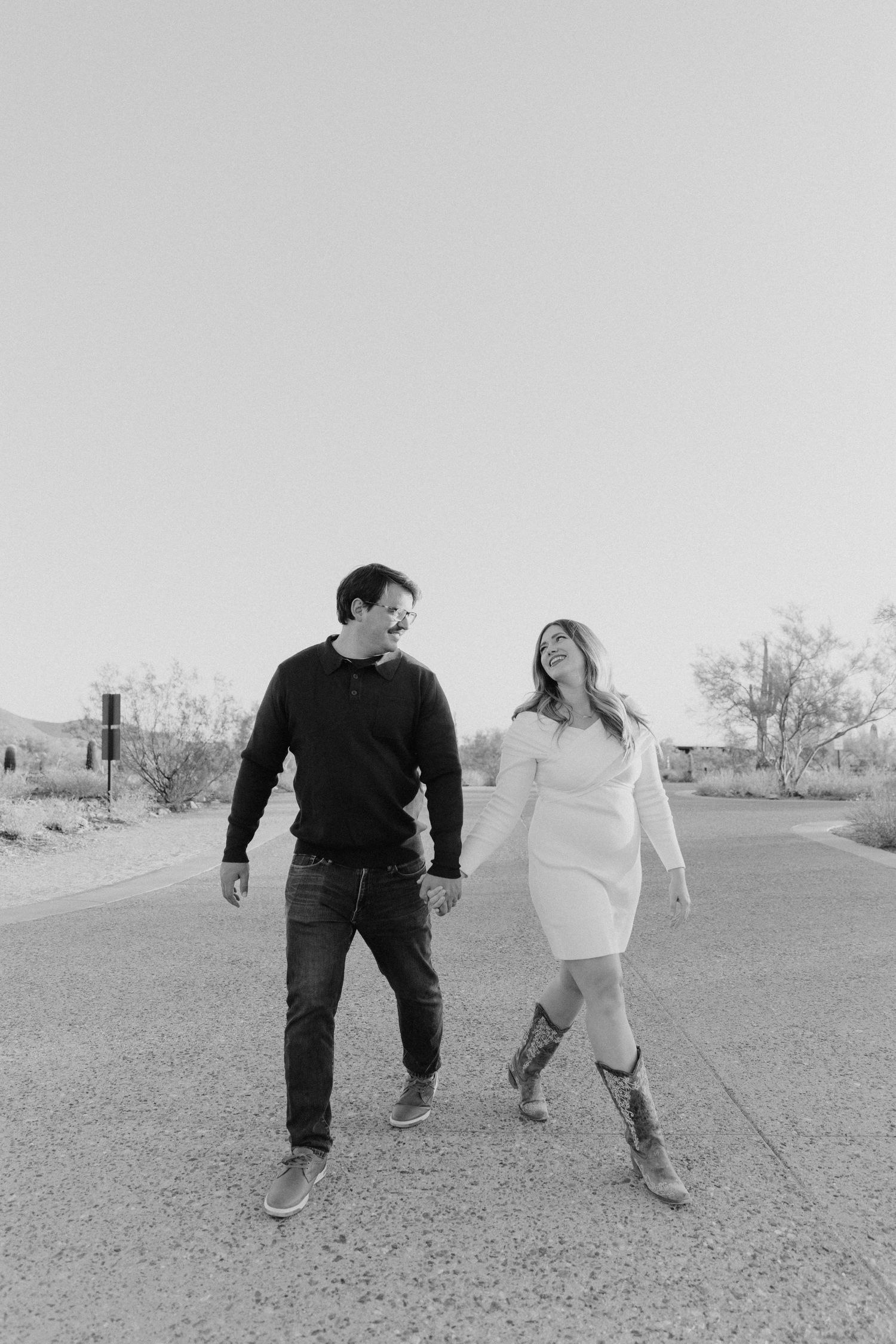 Black and white photo of couple walking together on desert path.