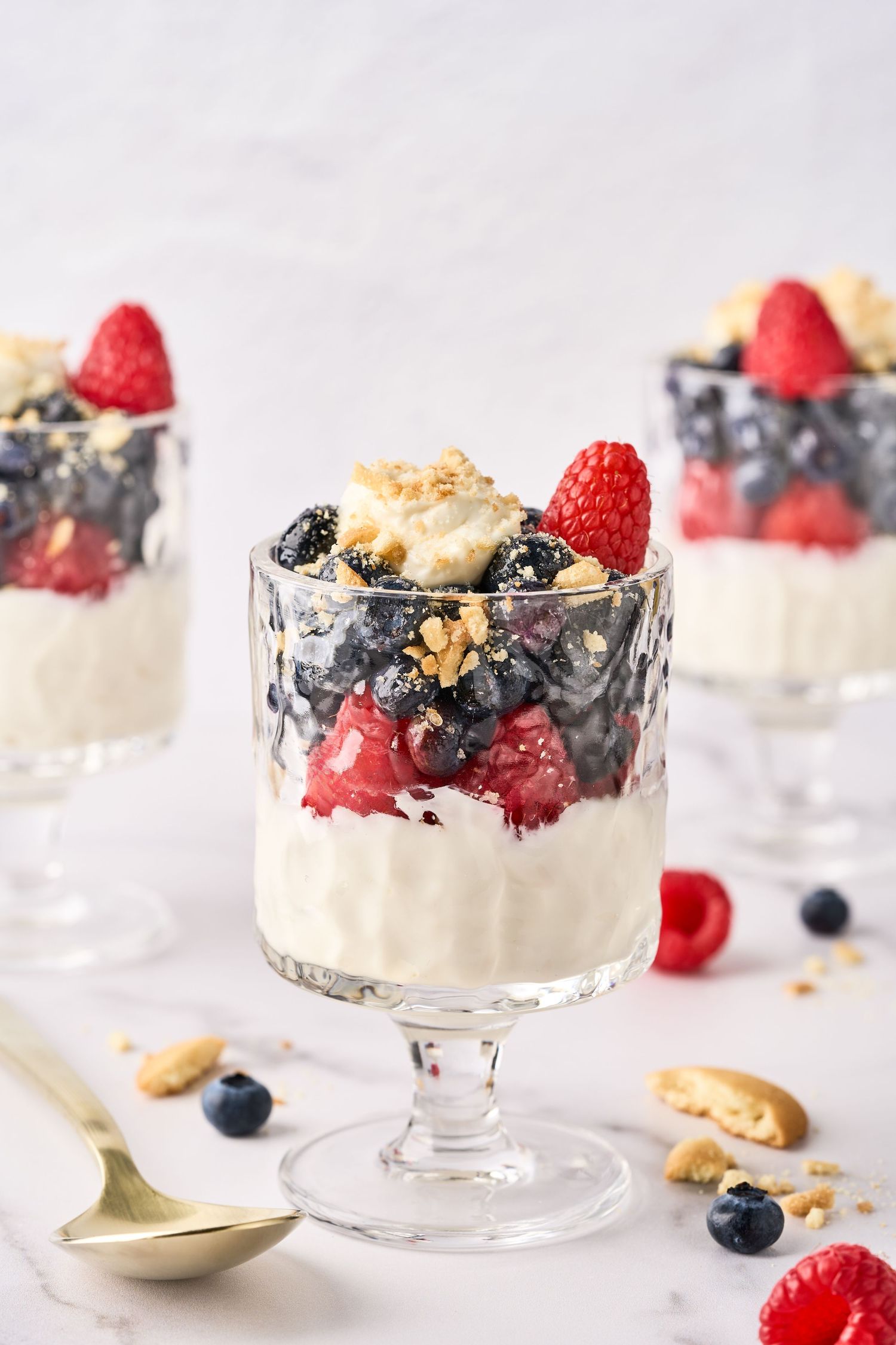 Layered yogurt parfait with fresh raspberries, blueberries, granola and nuts served in elegant glass dessert cups.
