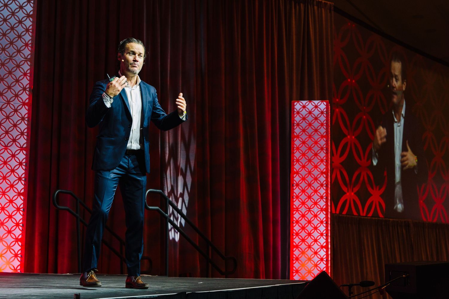 Stage performance with dramatic lighting and red checkered backdrop panels.