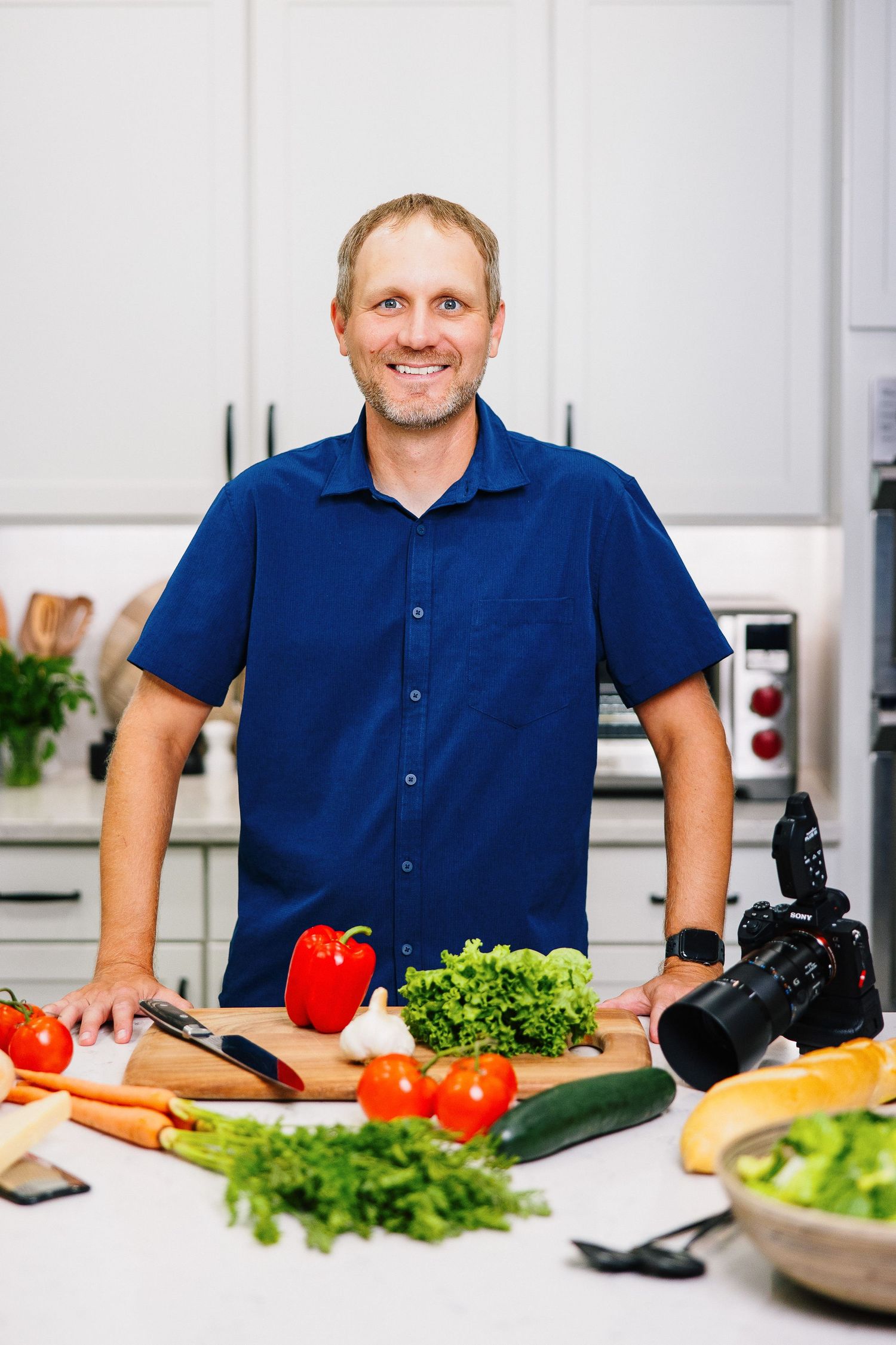 Food photographer in blue shirt preparing fresh vegetables and produce for photo shoot.
