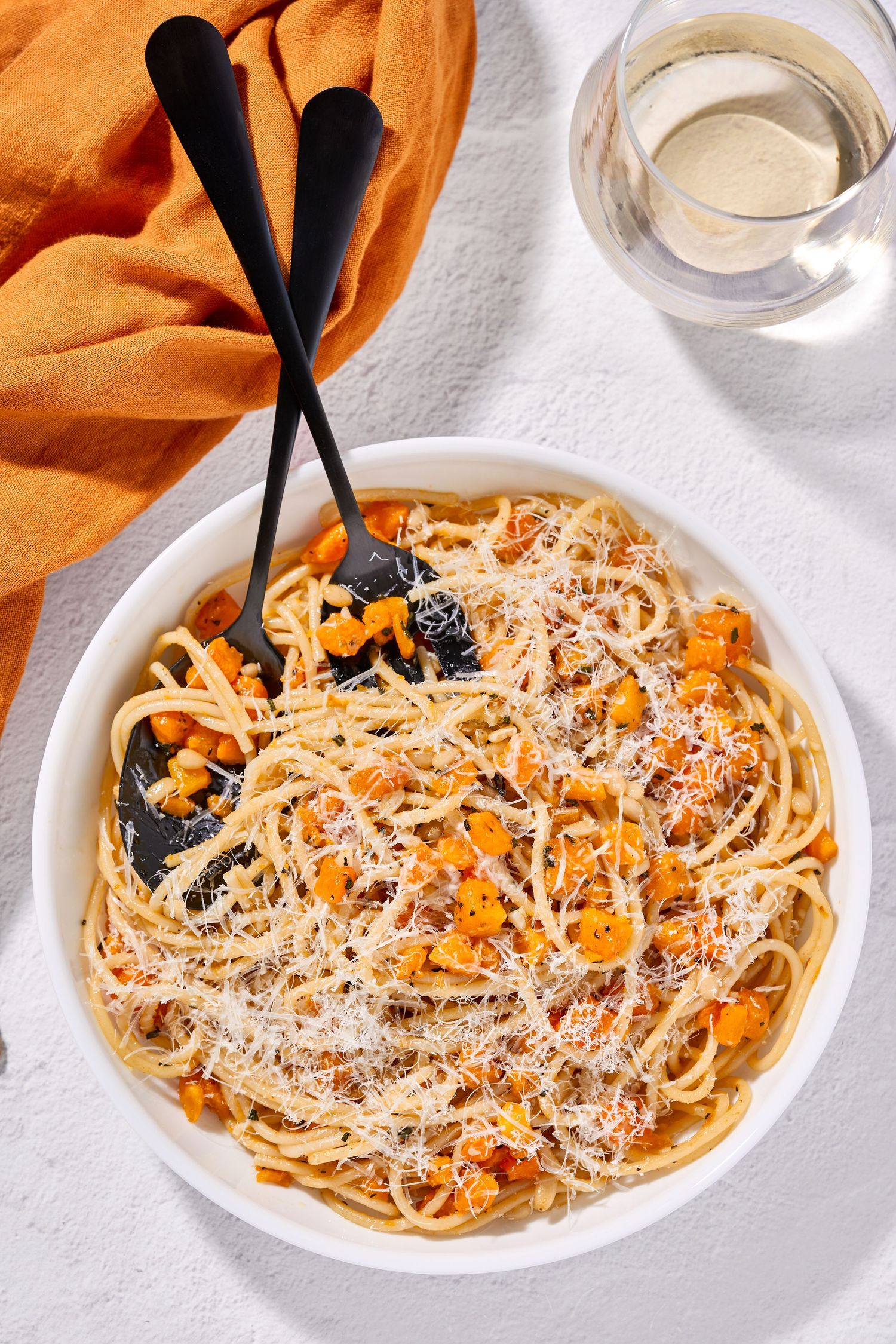 Creamy pasta dish with grated parmesan cheese and vegetables served on white plates.
